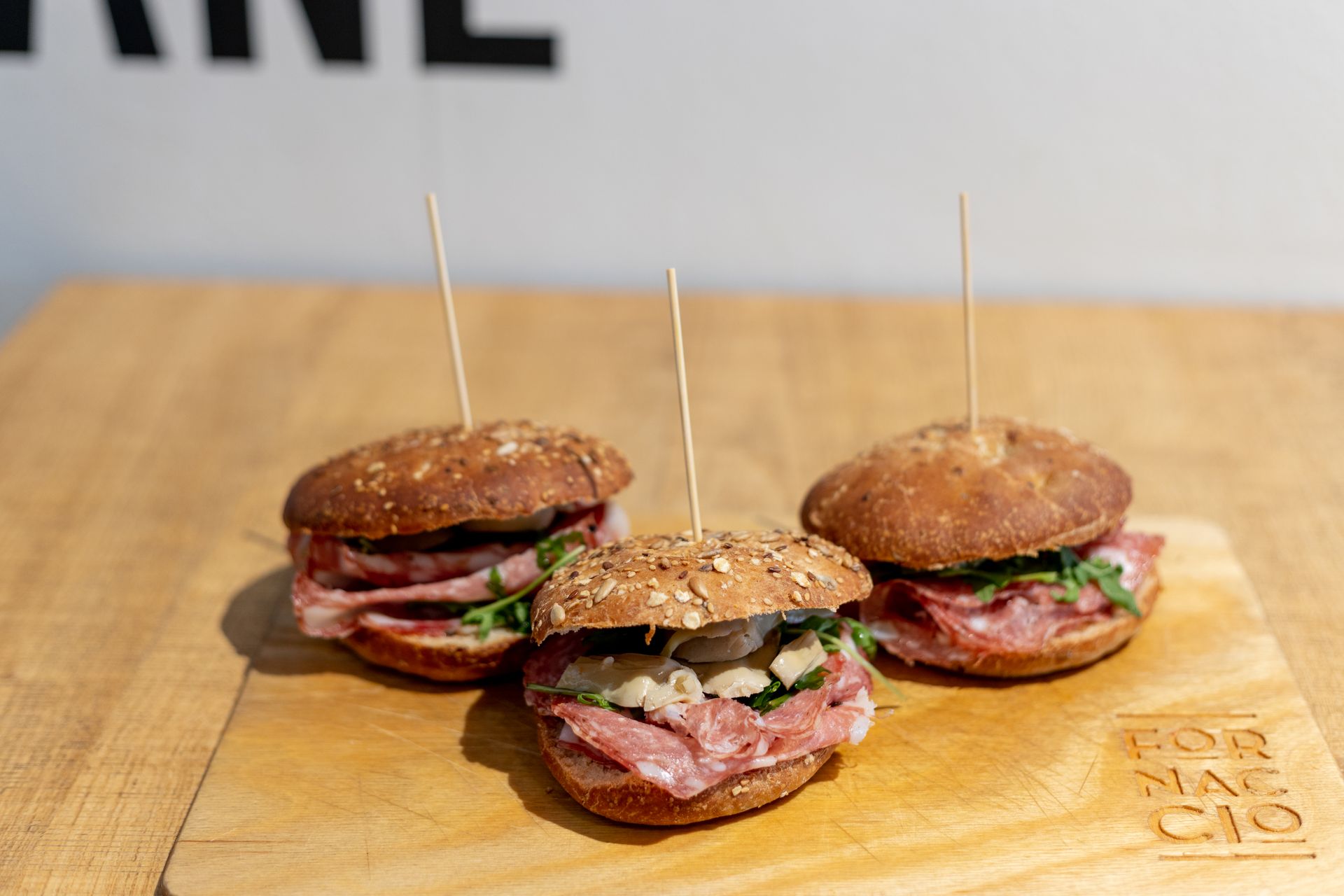 Tre piccoli panini su un tagliere di legno, tenuti insieme con degli stuzzicadenti.
