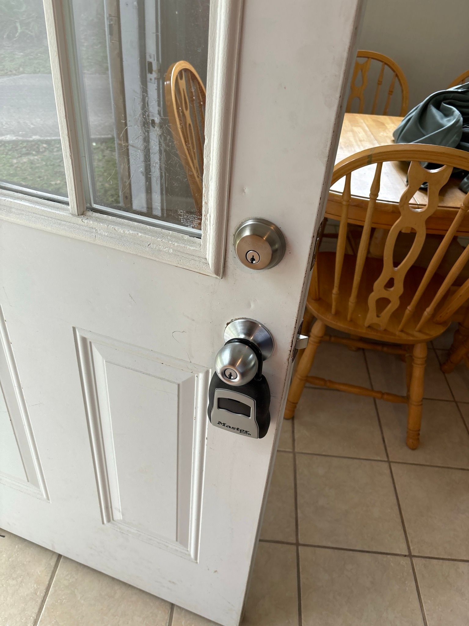 A white door with a lock on it is open to a dining room with a table and chairs.