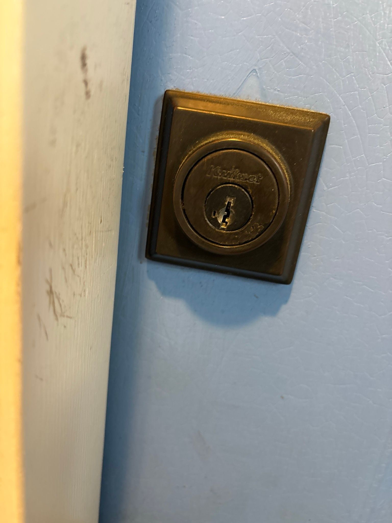 A close up of a door lock on a blue wall.