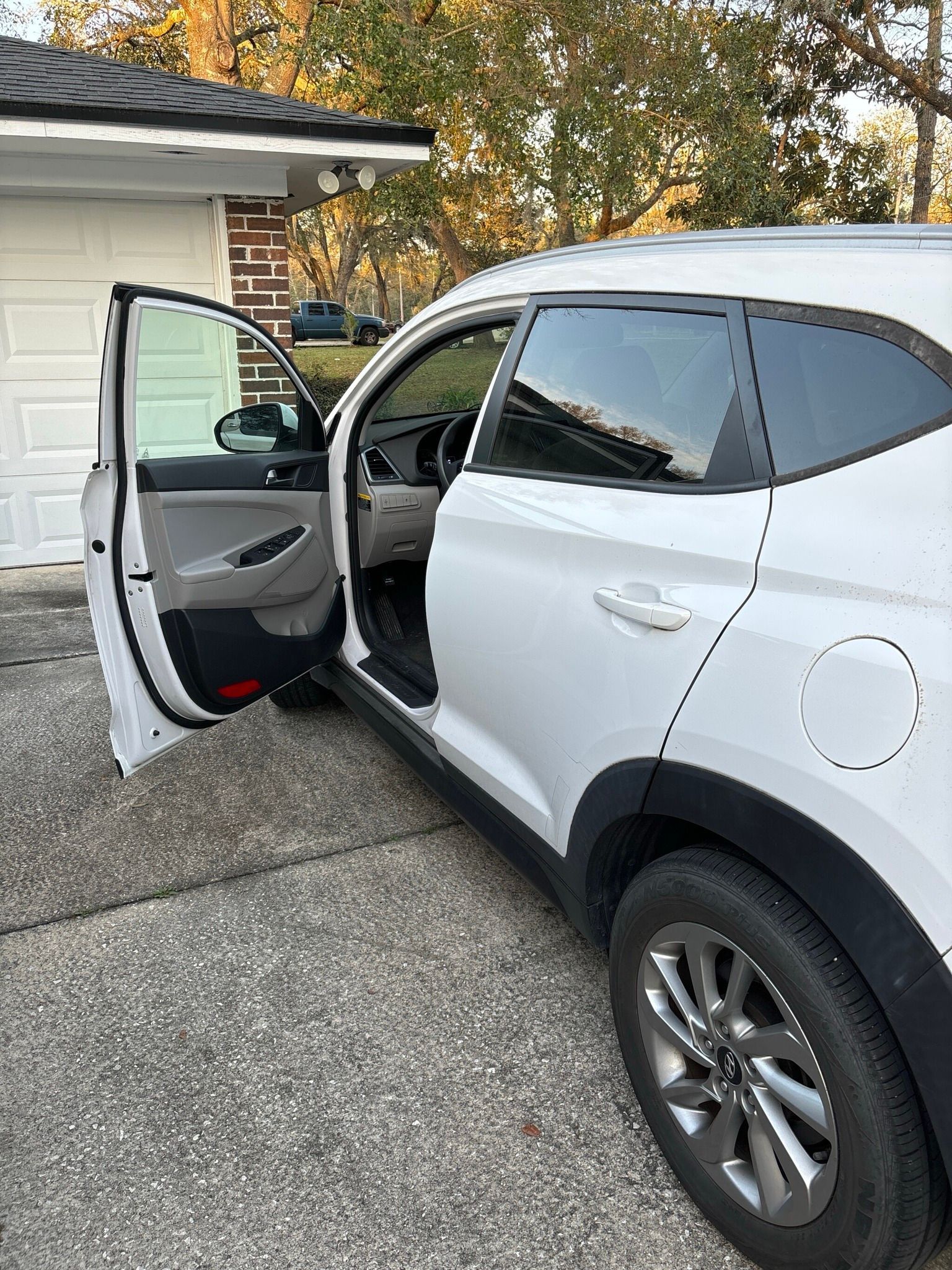 A white car is parked in front of a garage with its doors open.