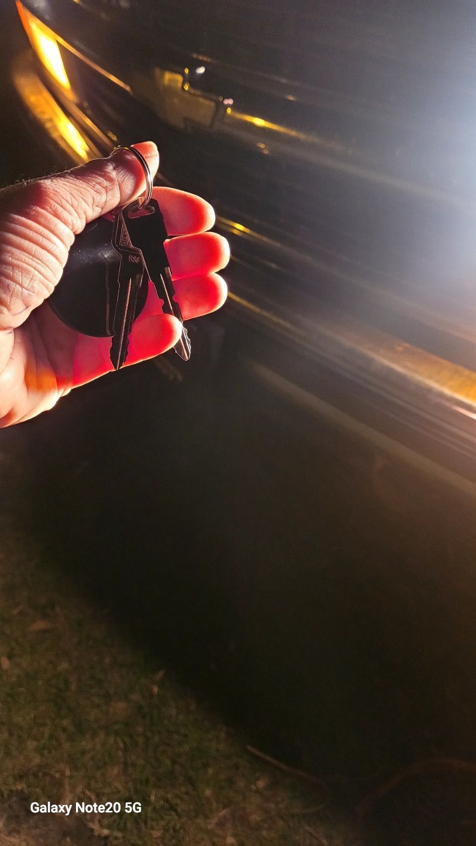 A person is holding a pair of car keys in their hand.