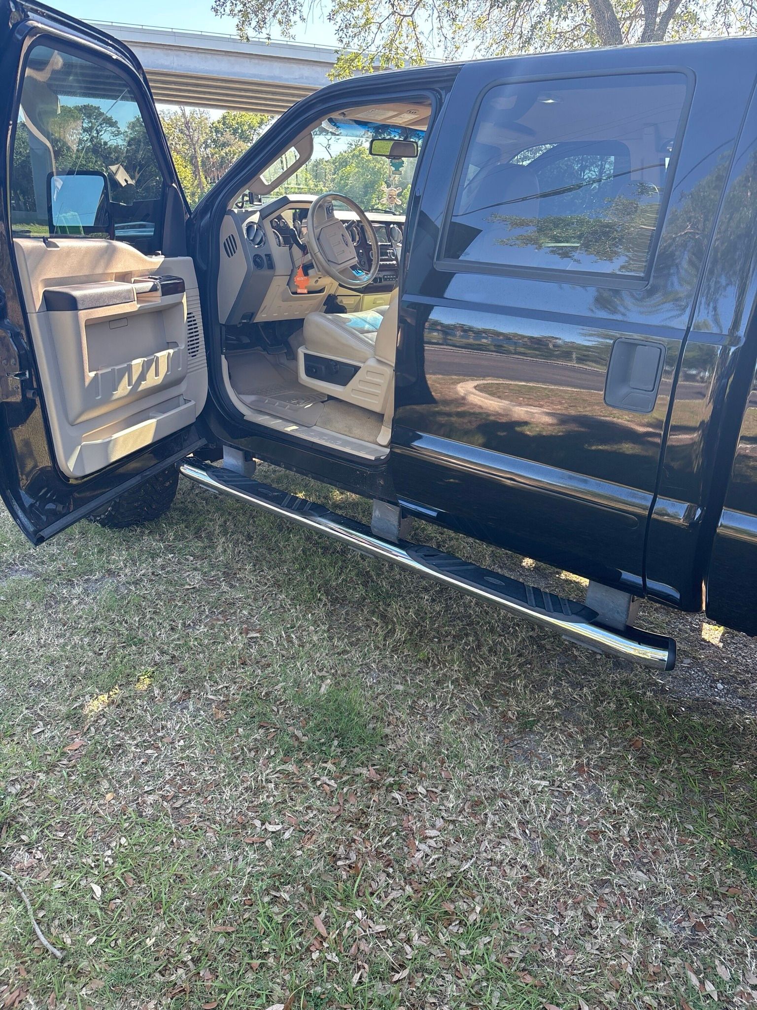 A black truck with its doors open is parked in the grass.