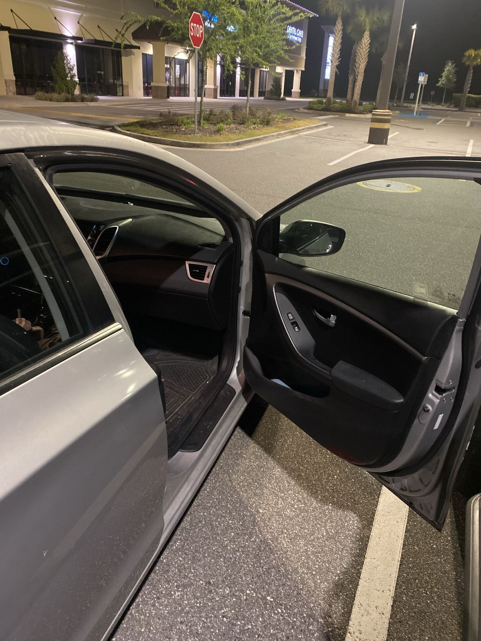 A car is parked in a parking lot with the door open.