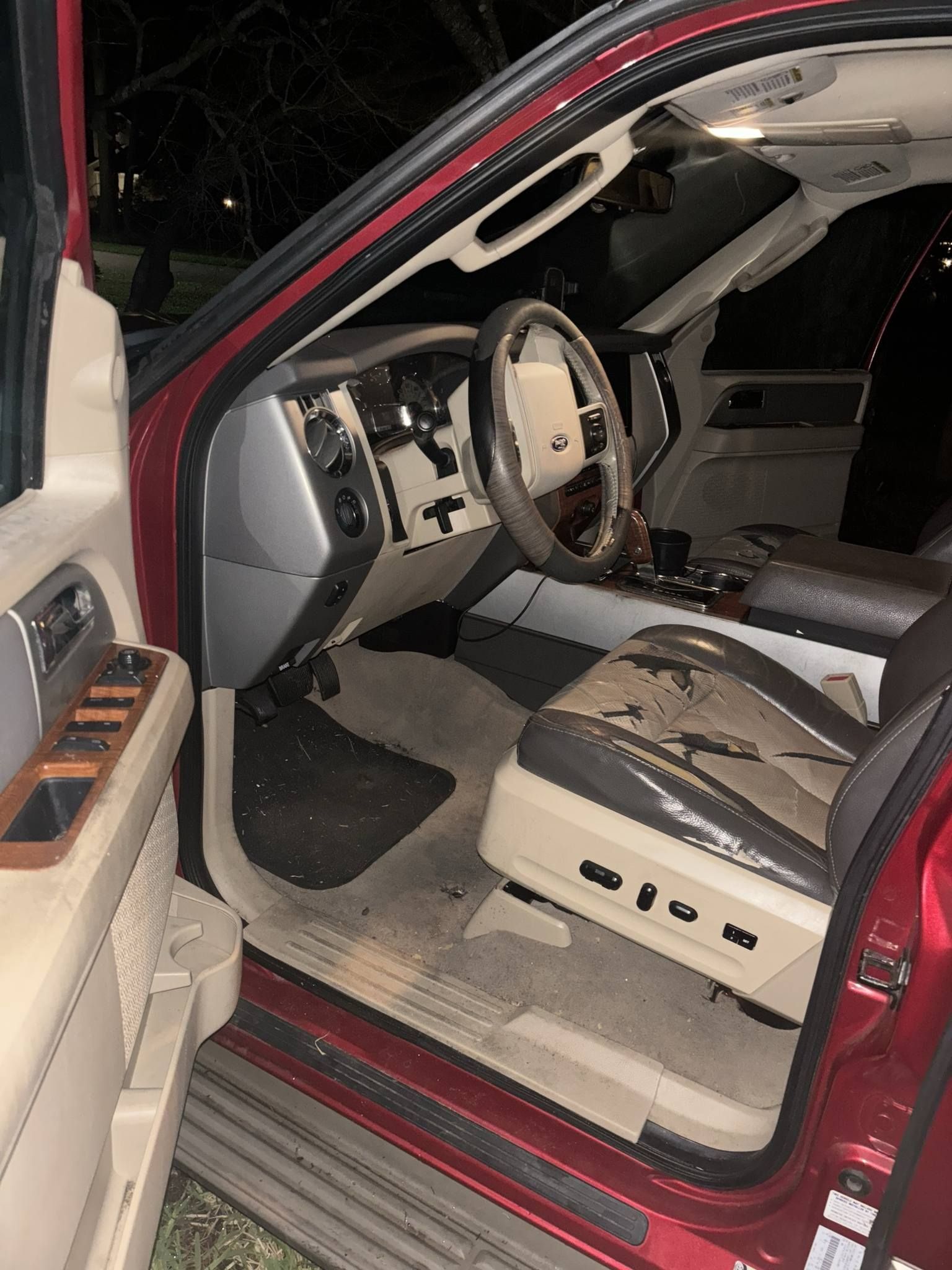 The inside of a red car with the door open at night.