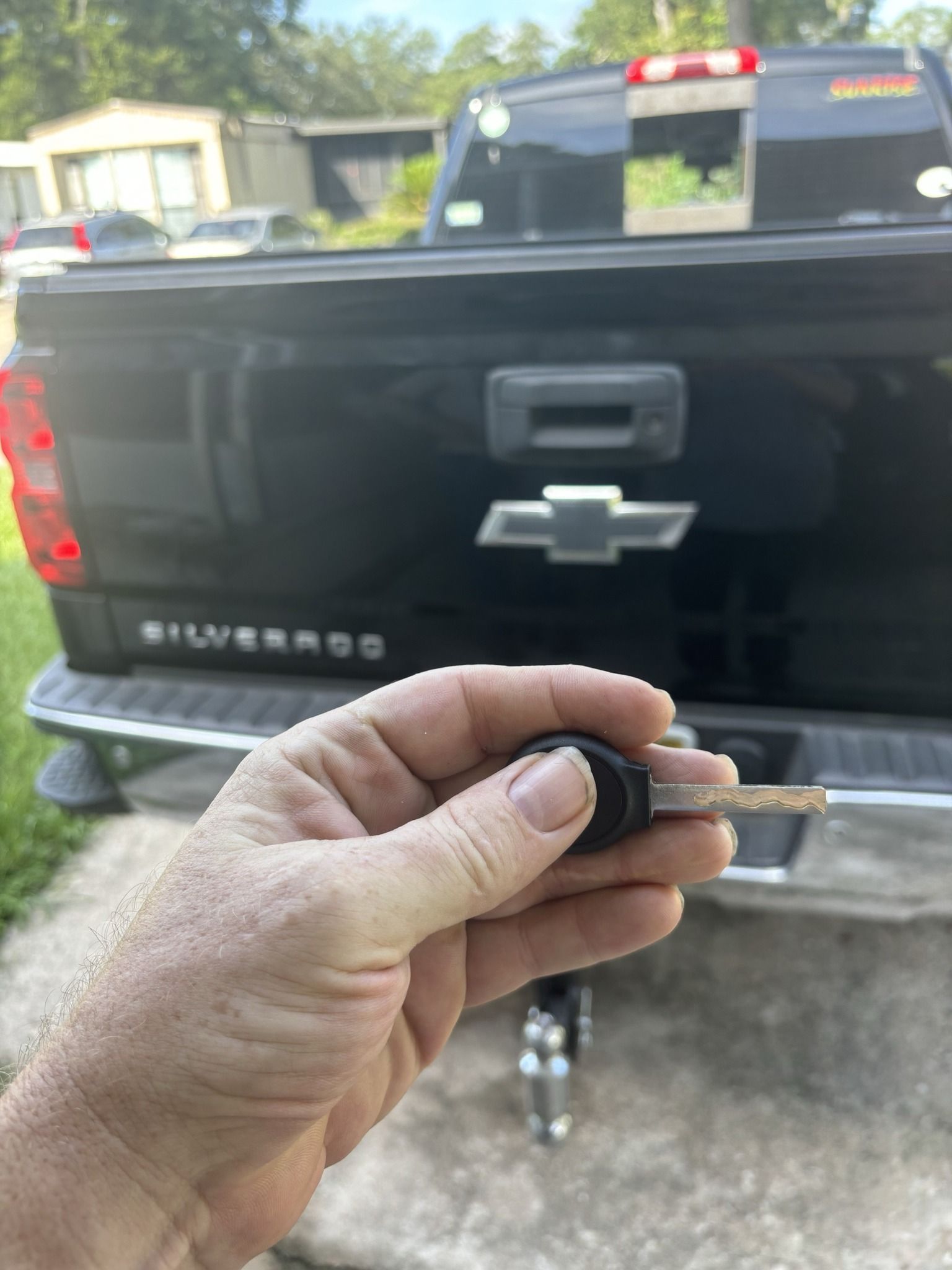 A person is holding a key in front of a chevrolet silverado truck.