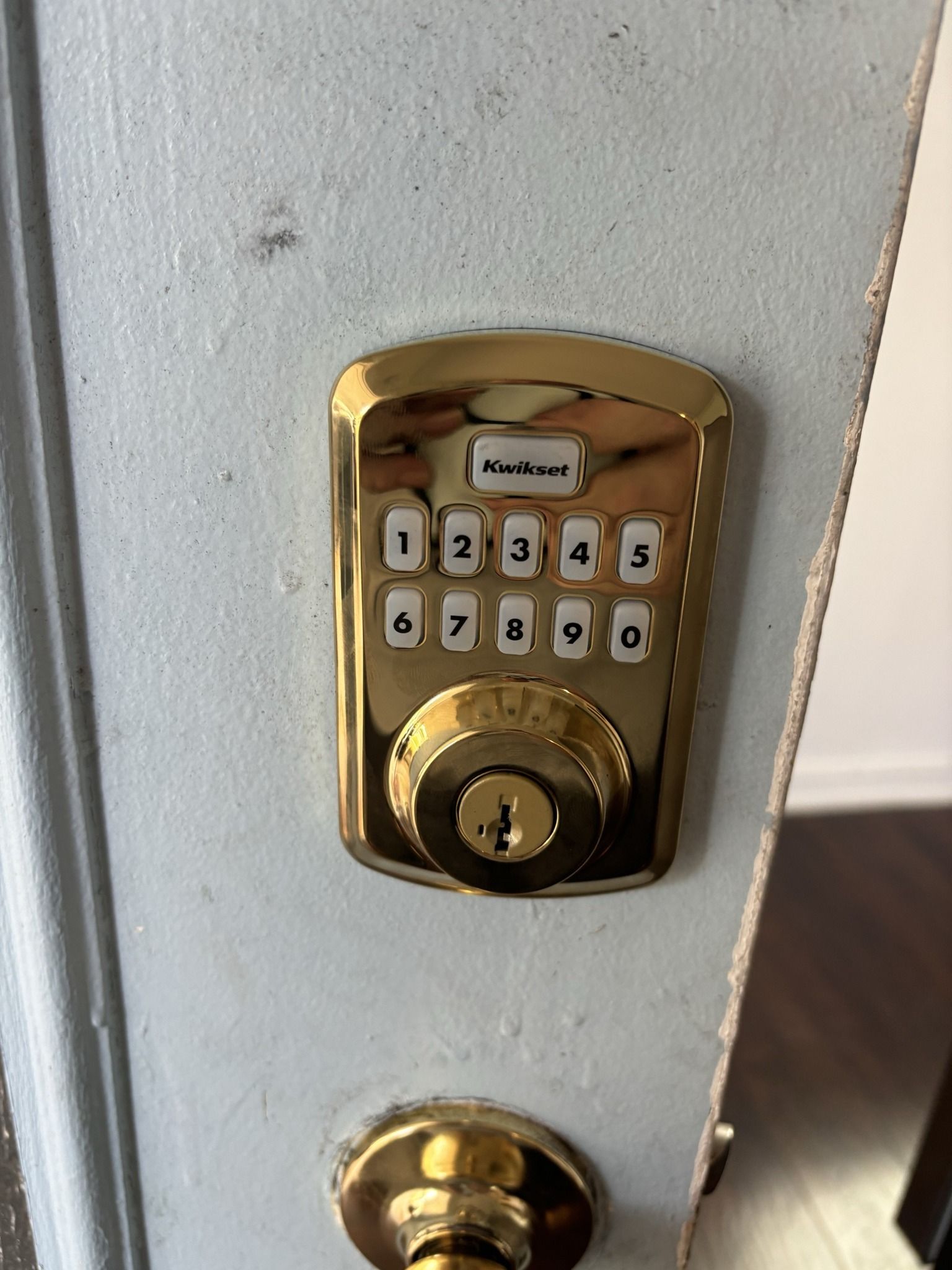 A close up of a gold door lock on a white door.