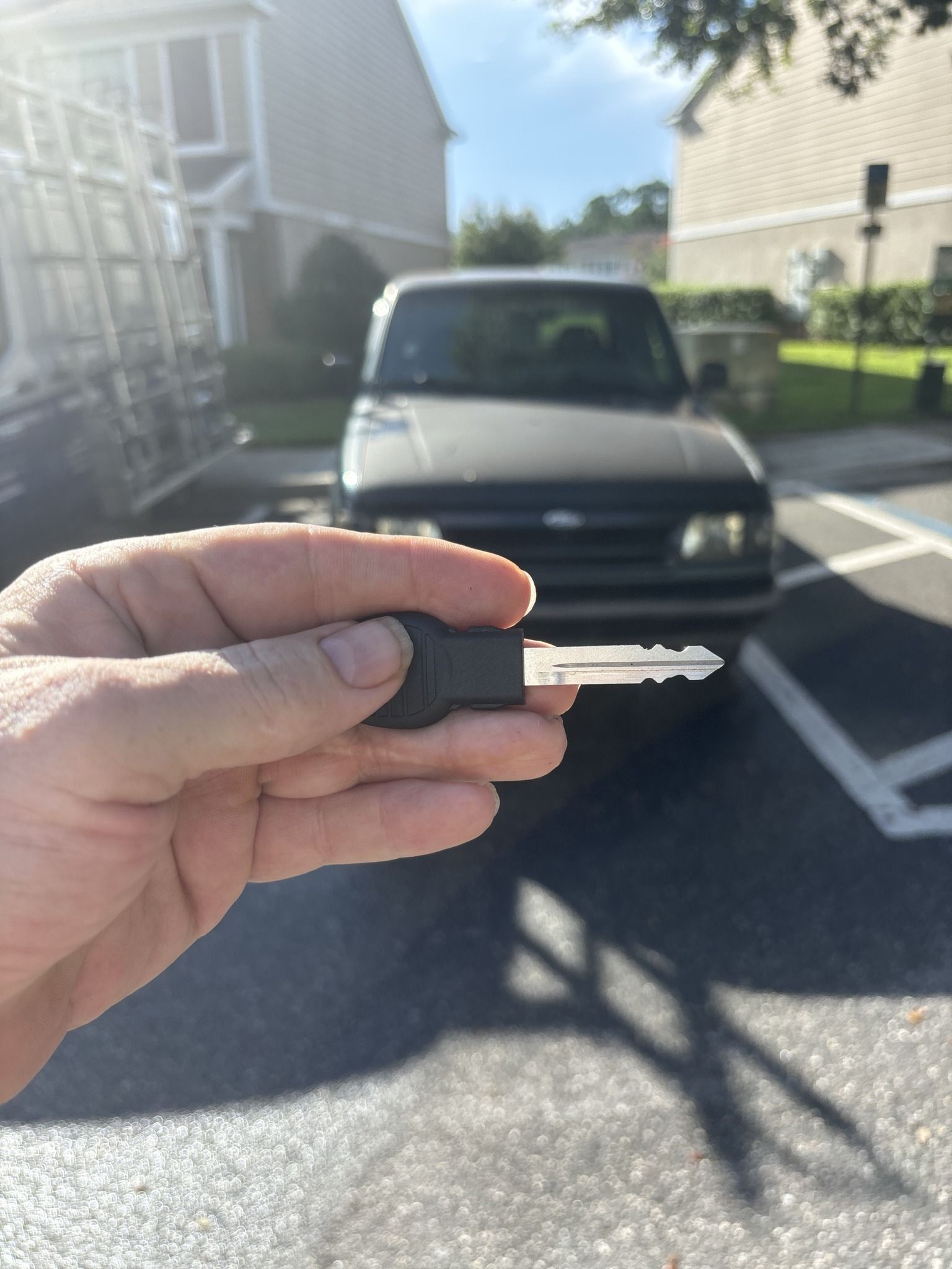 A person is holding a car key in front of a car.