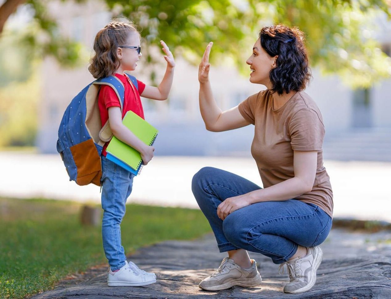 Mother and daughter give each other a high five before school starts.