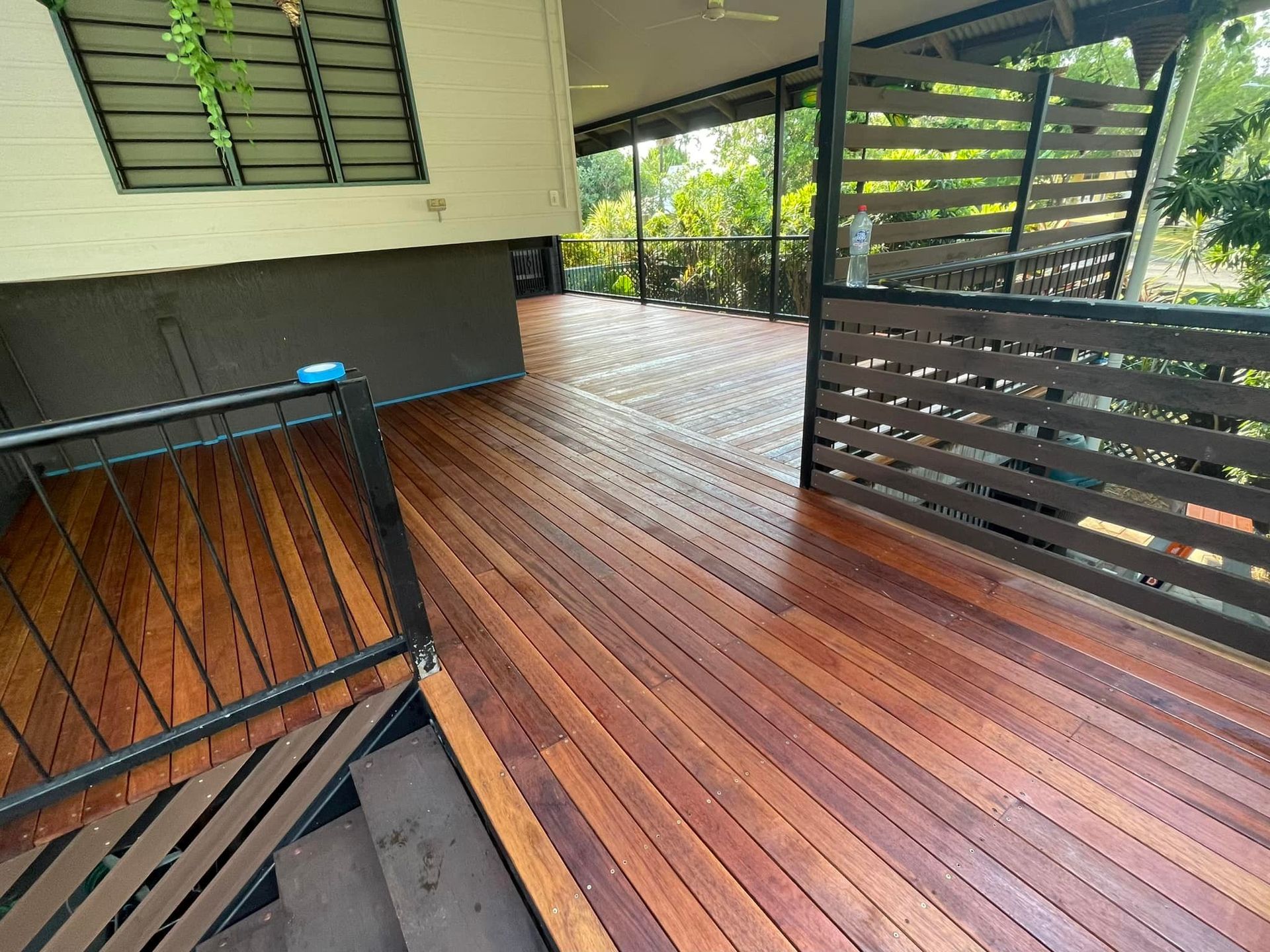 Wooden deck with dark railings, partially covered by a roof, overlooking greenery — Northco Constructions In Nightcliff, NT