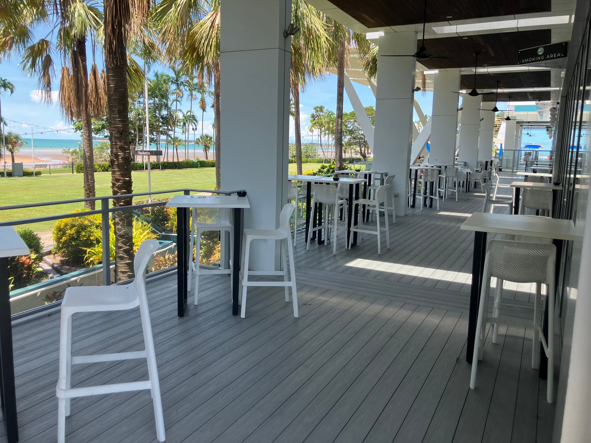 Outdoor Patio With White Tables and Chairs, Overlooking a Grassy Area and Beach — Northco Constructions In Muirhead, NT