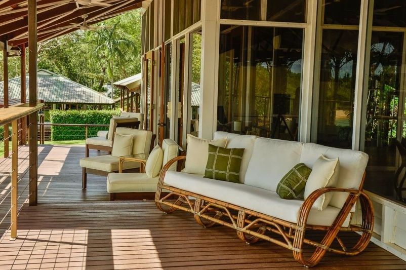A Porch With a Woven White Sofa and Chairs, With Green Cushions — Northco Constructions In Muirhead, NT