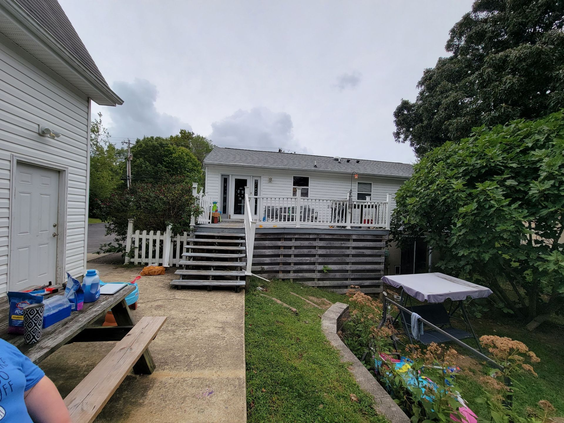 A woman is sitting at a picnic table in front of a house.