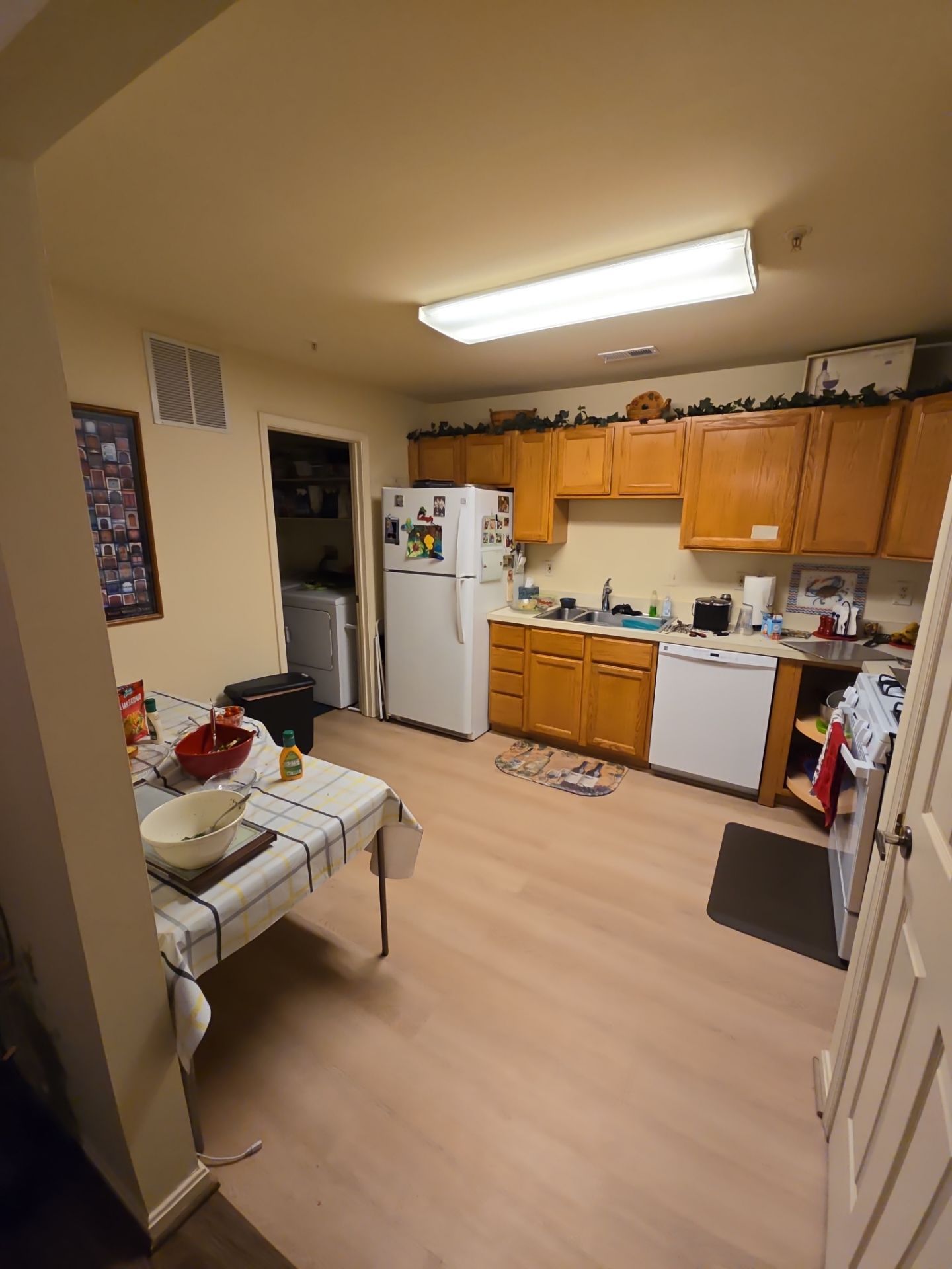 A kitchen with wooden cabinets , white appliances , a table and a refrigerator.