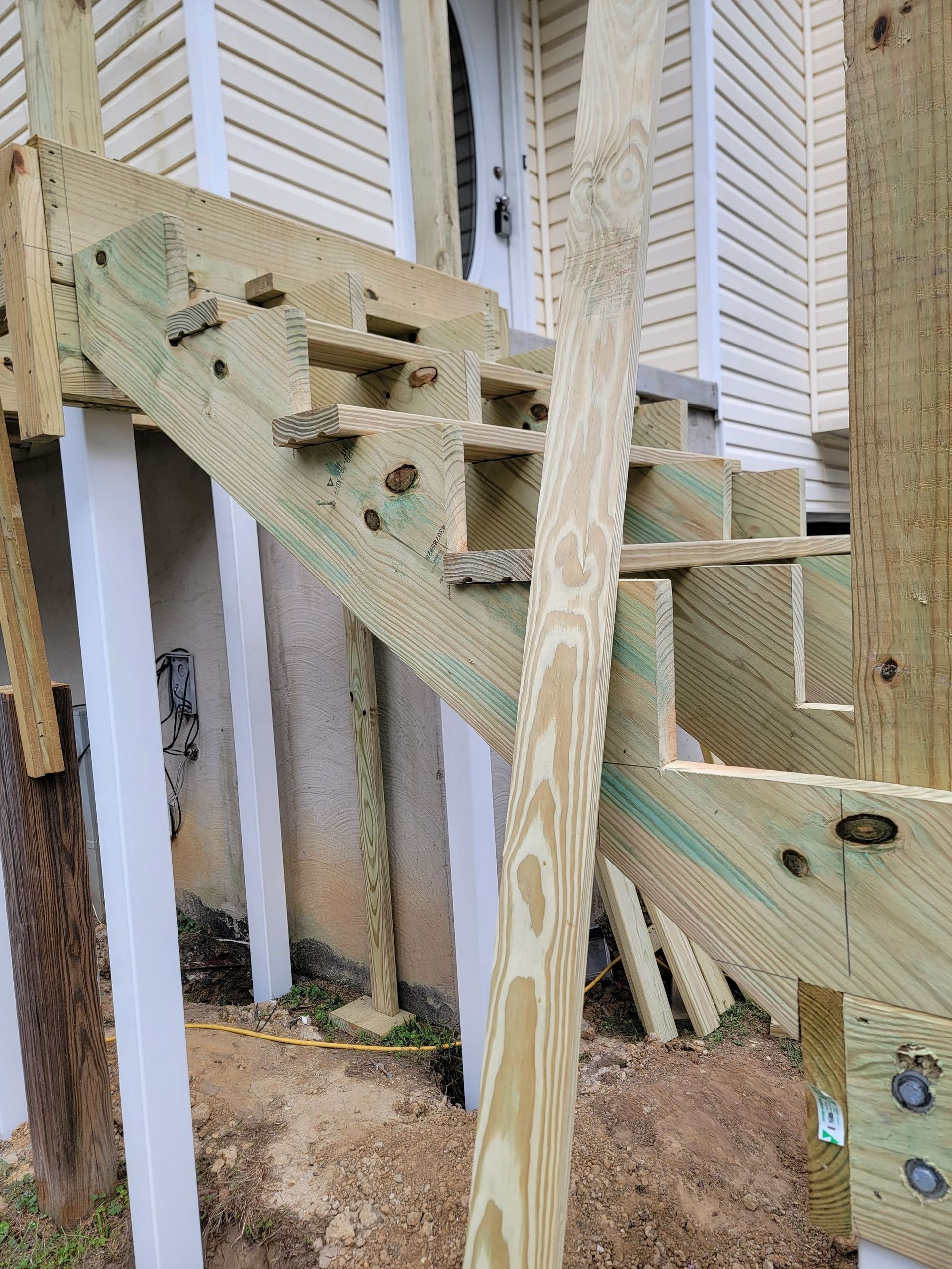 A wooden staircase is being built on the side of a house.