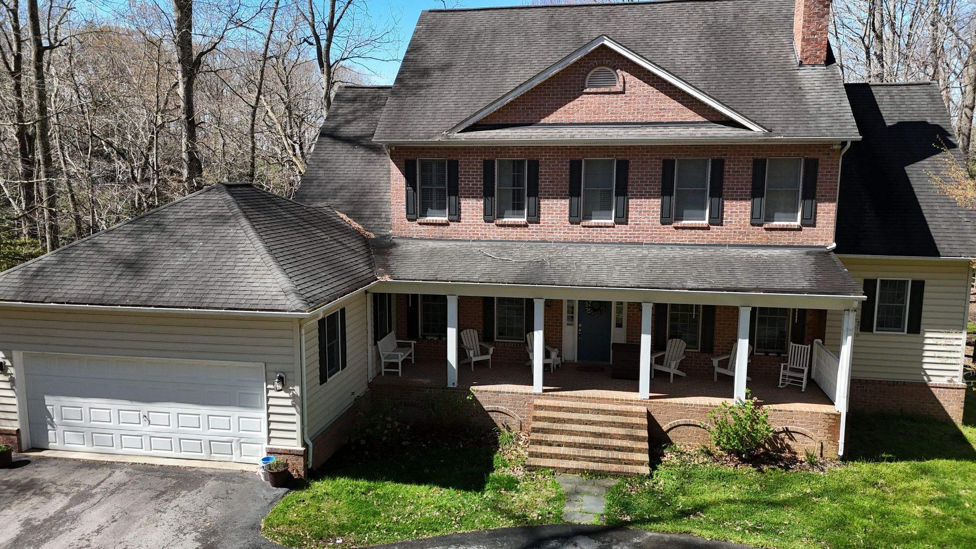 A large brick house with a large porch and a garage.