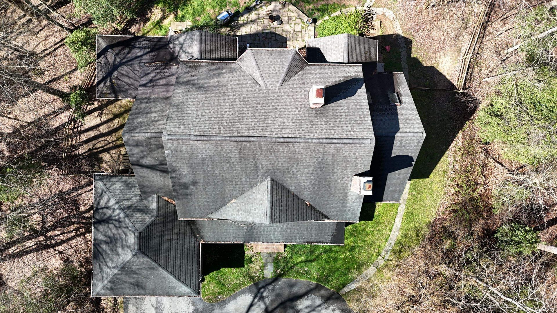 An aerial view of a large house in the middle of a forest.