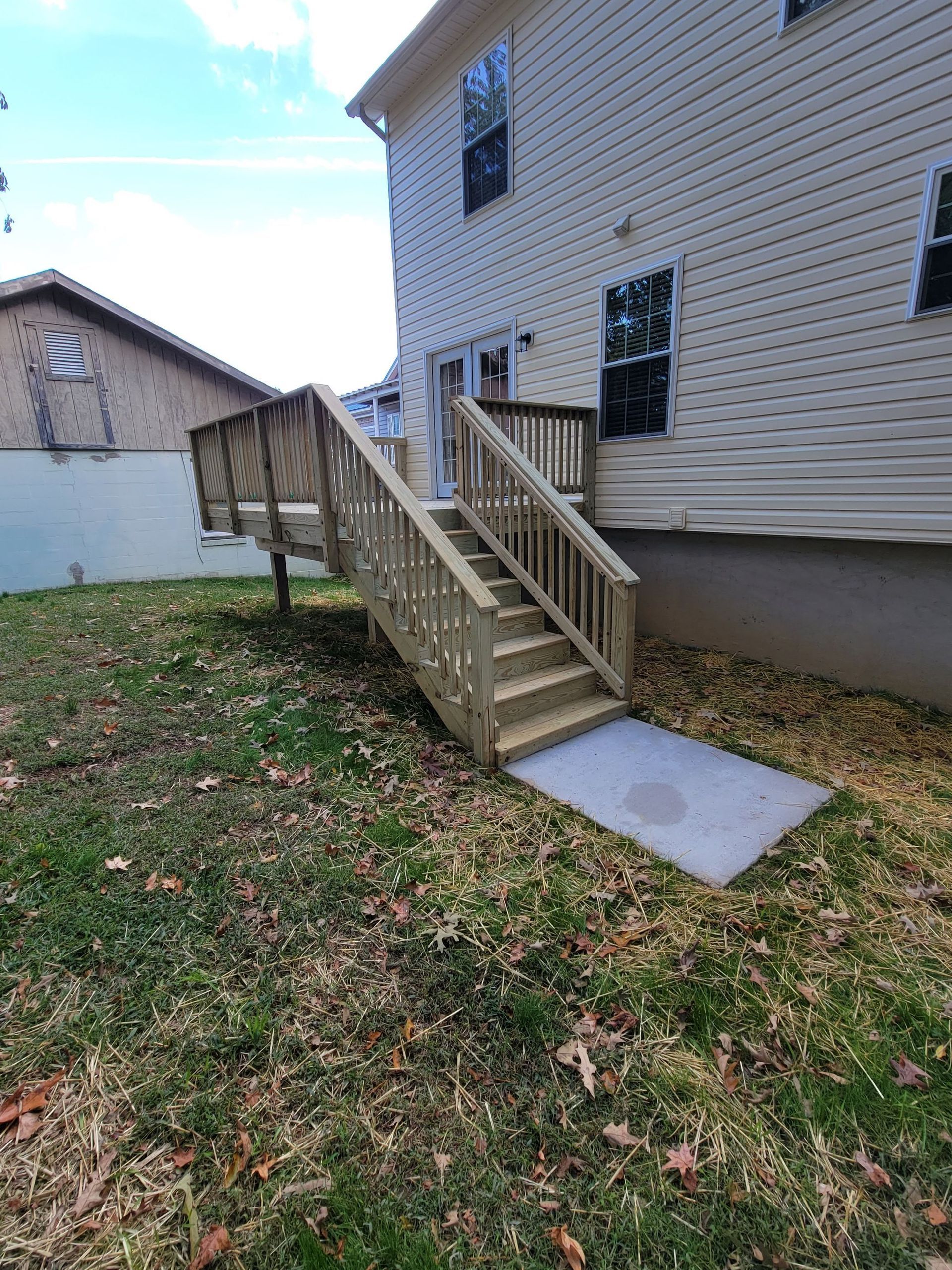 A wooden deck with stairs leading up to the back of a house.