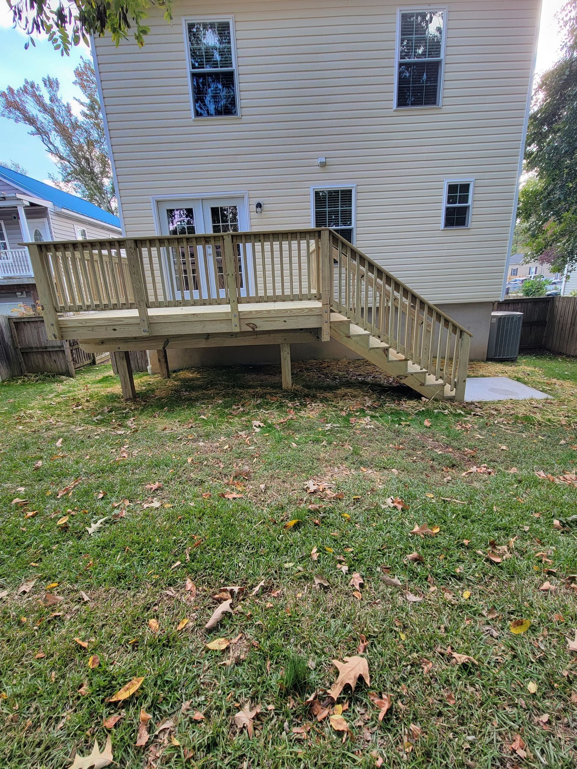 A wooden deck with stairs is in the backyard of a house.