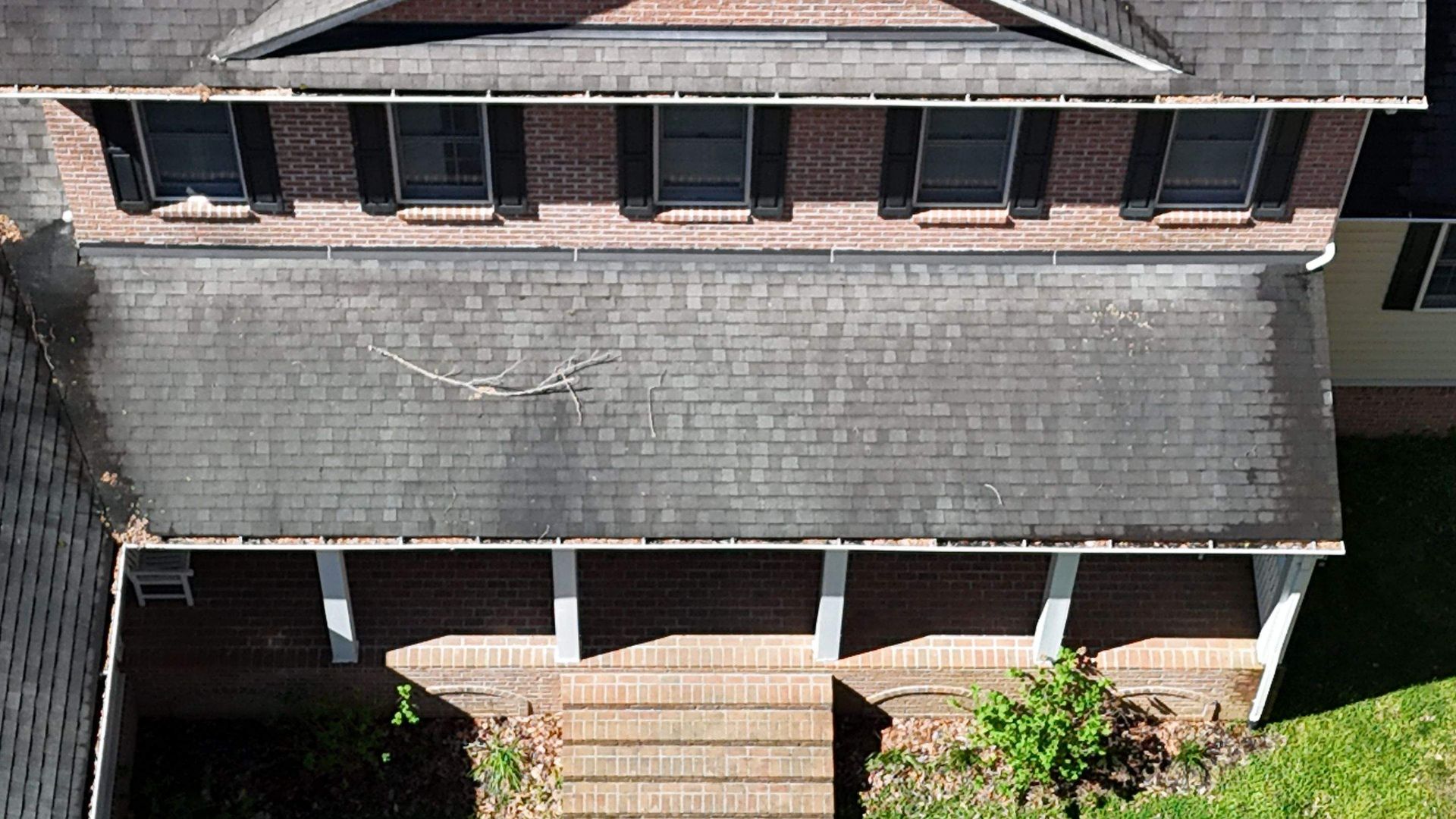 An aerial view of a brick house with a porch and stairs.