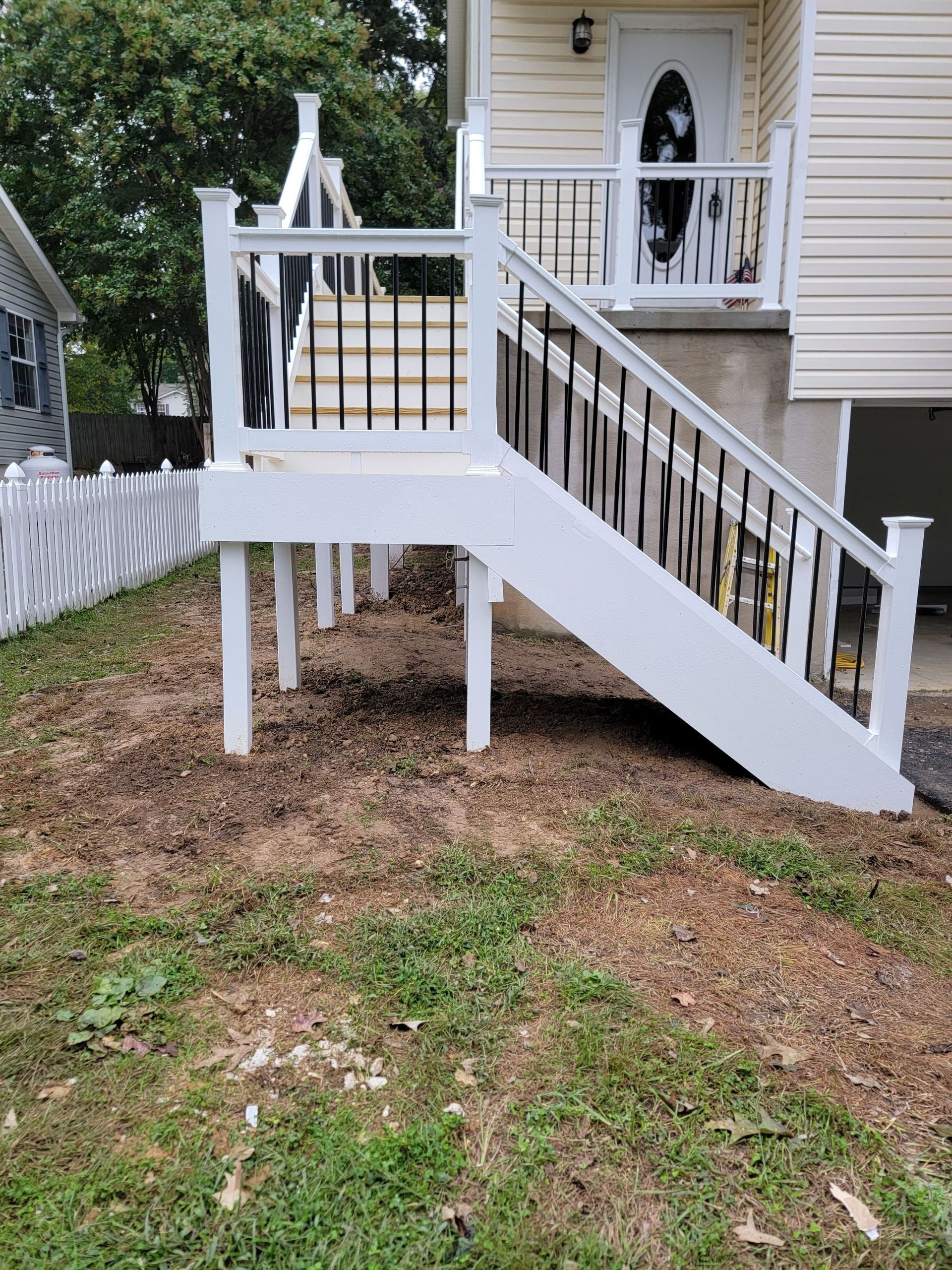 A white deck with stairs leading up to the front of a house.