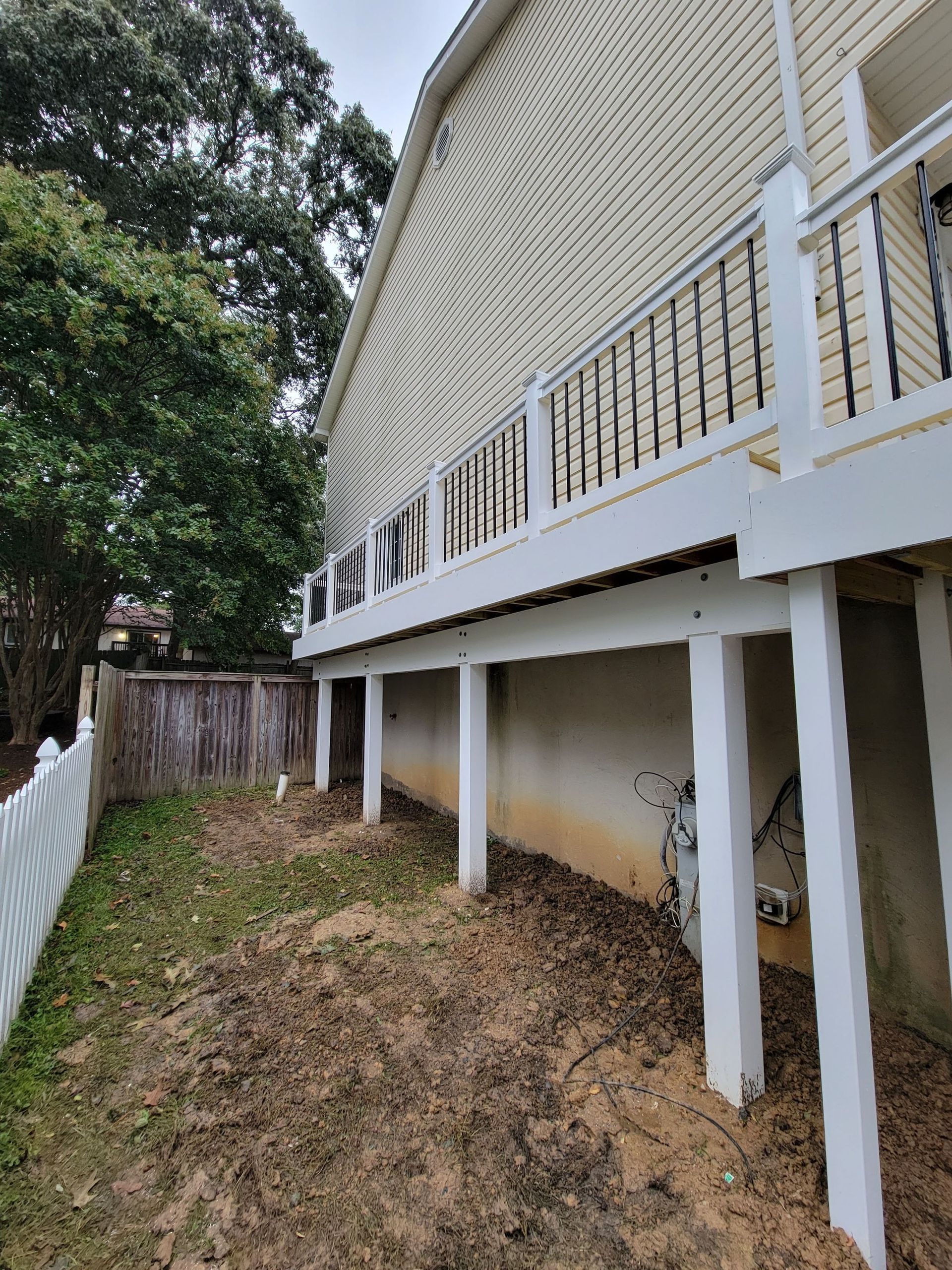 A house with a deck and a white fence in the backyard.