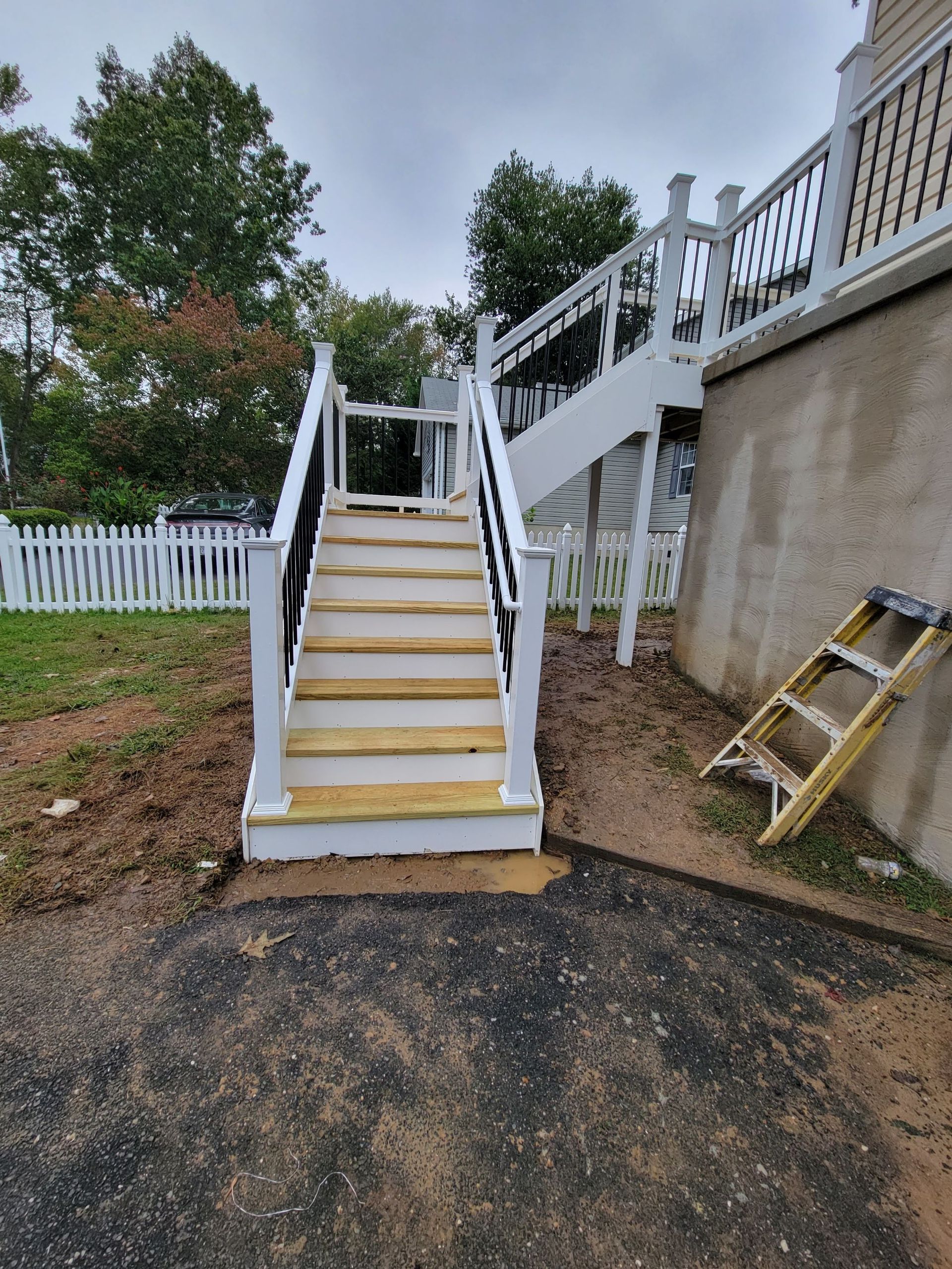 A ladder is sitting next to a set of stairs leading up to a deck.