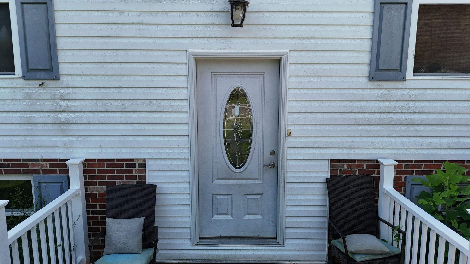 A white house with a gray door and a white railing