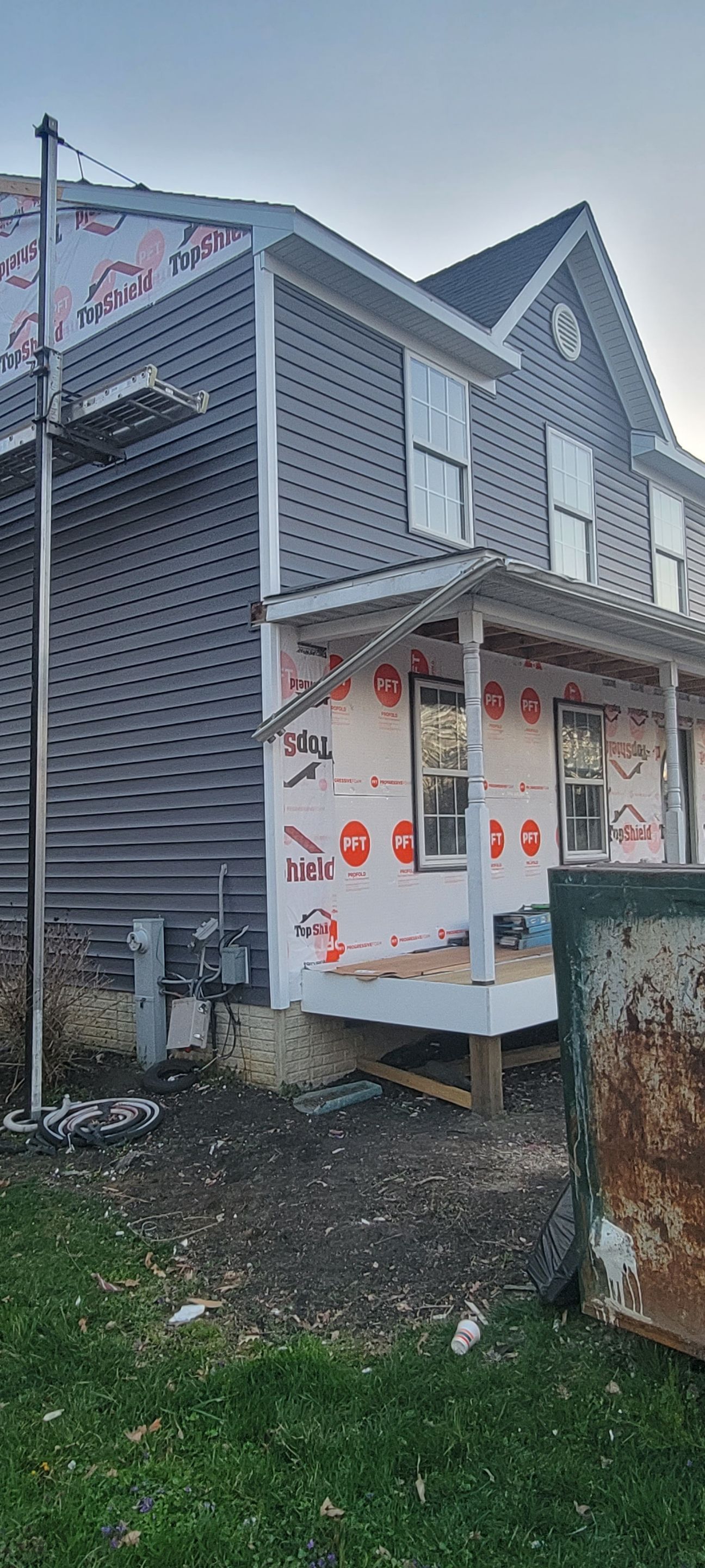 A house is being remodeled with siding and a porch.