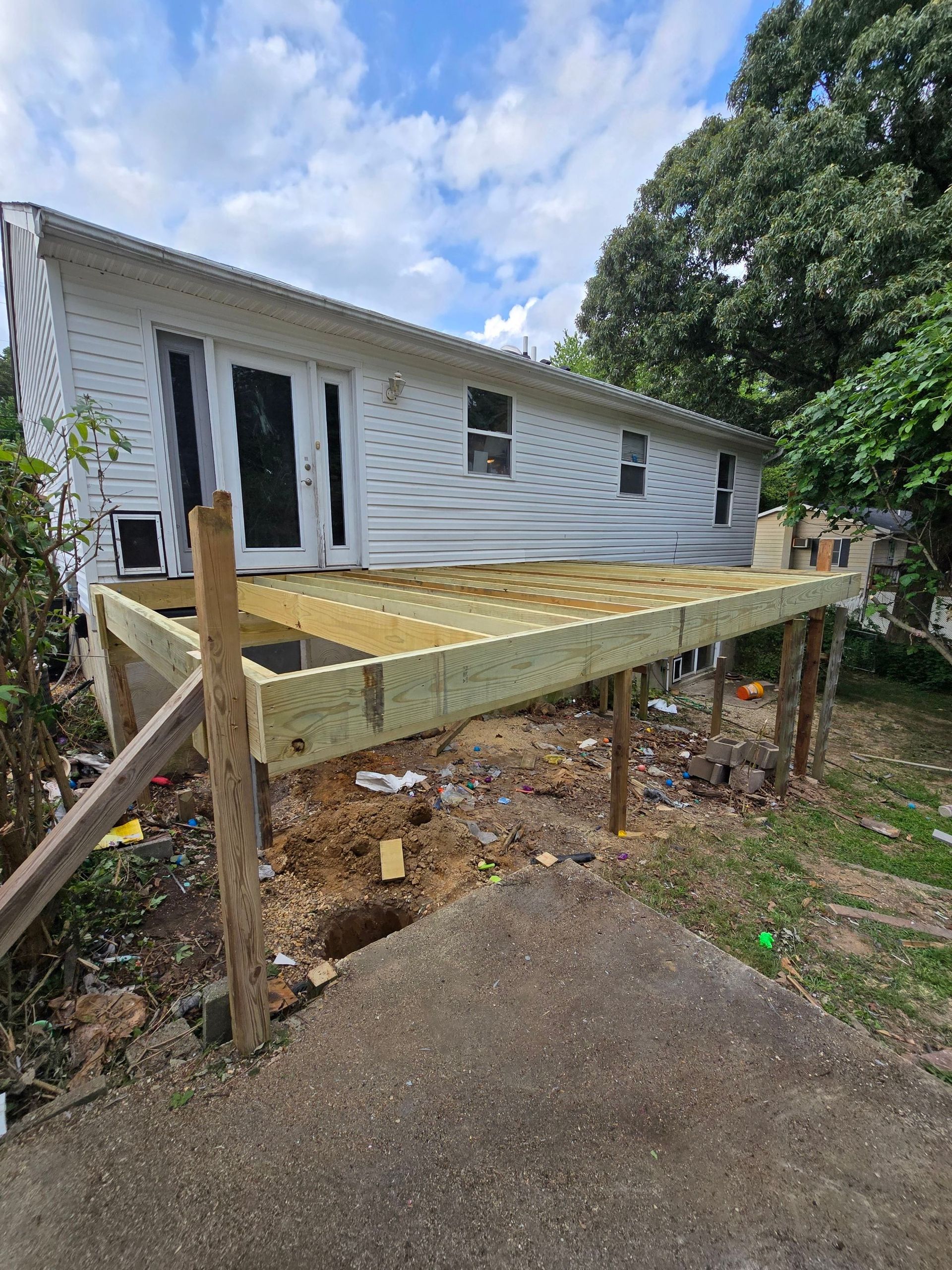 A wooden deck is being built in front of a white house.