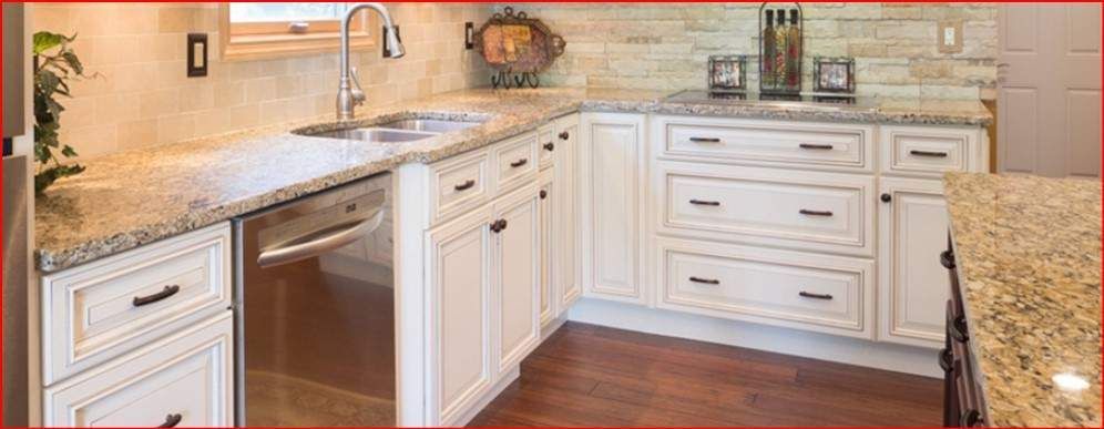A kitchen with white cabinets and granite counter tops.