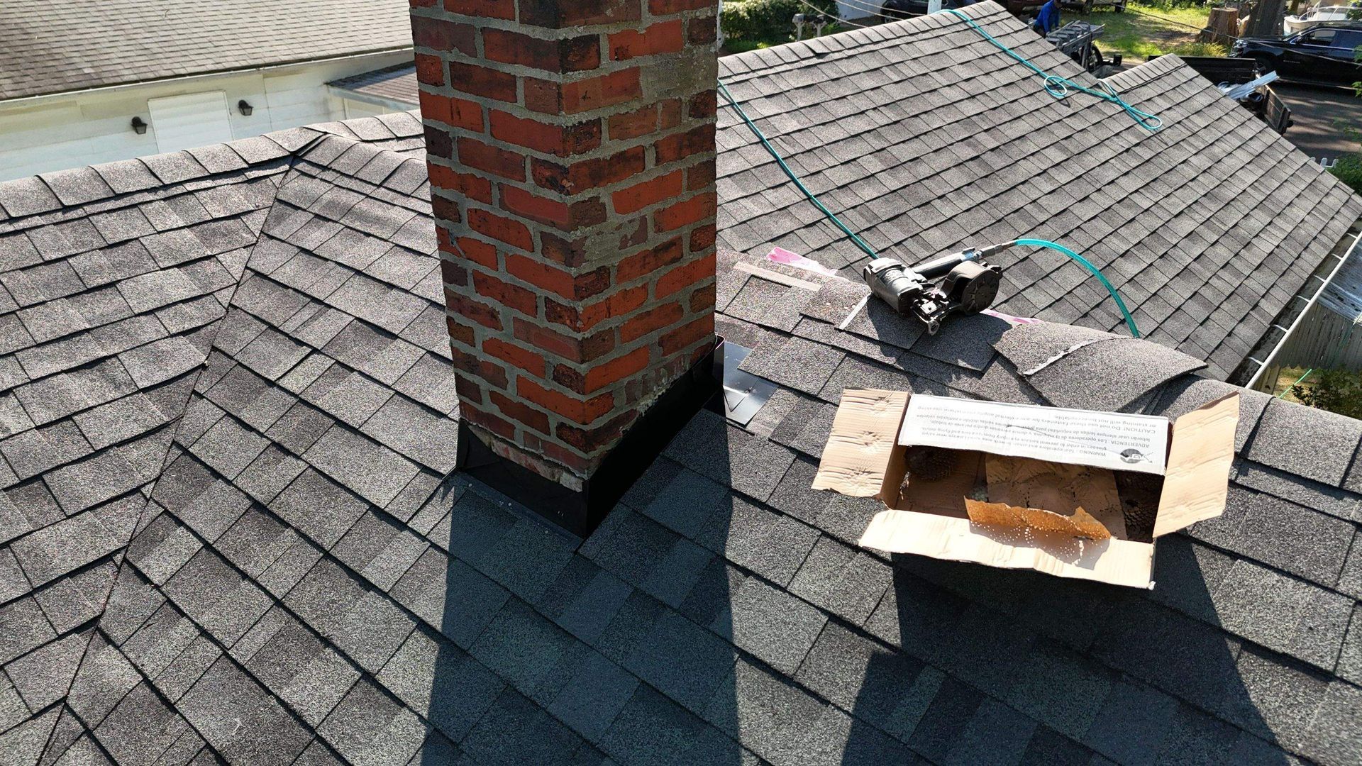A brick chimney is sitting on top of a roof next to a cardboard box.