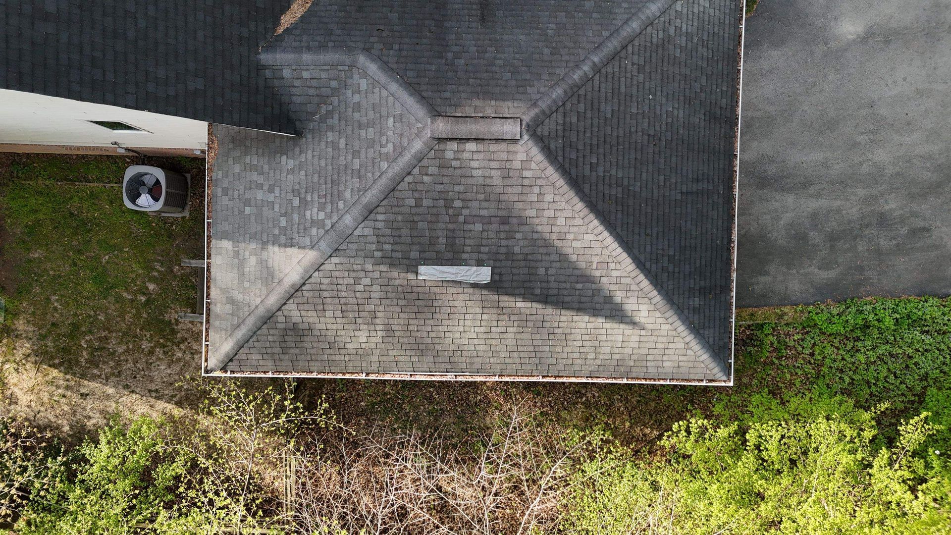 An aerial view of a house with a roof and a driveway.