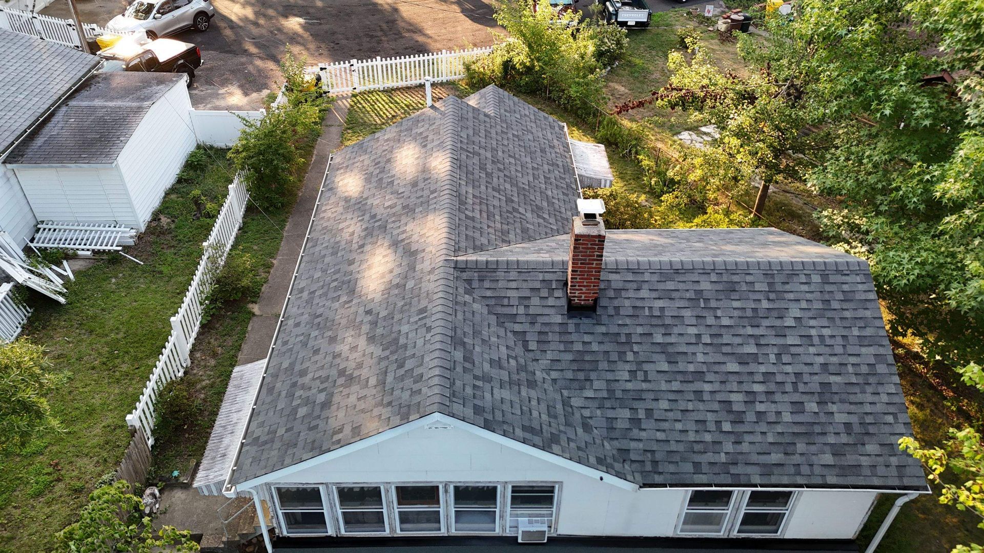 An aerial view of a house with a gray roof and a chimney.