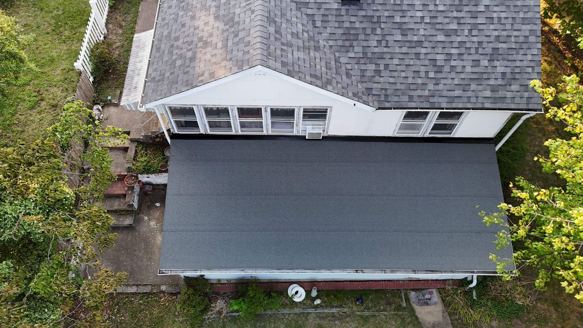An aerial view of a house with a gray roof surrounded by trees.