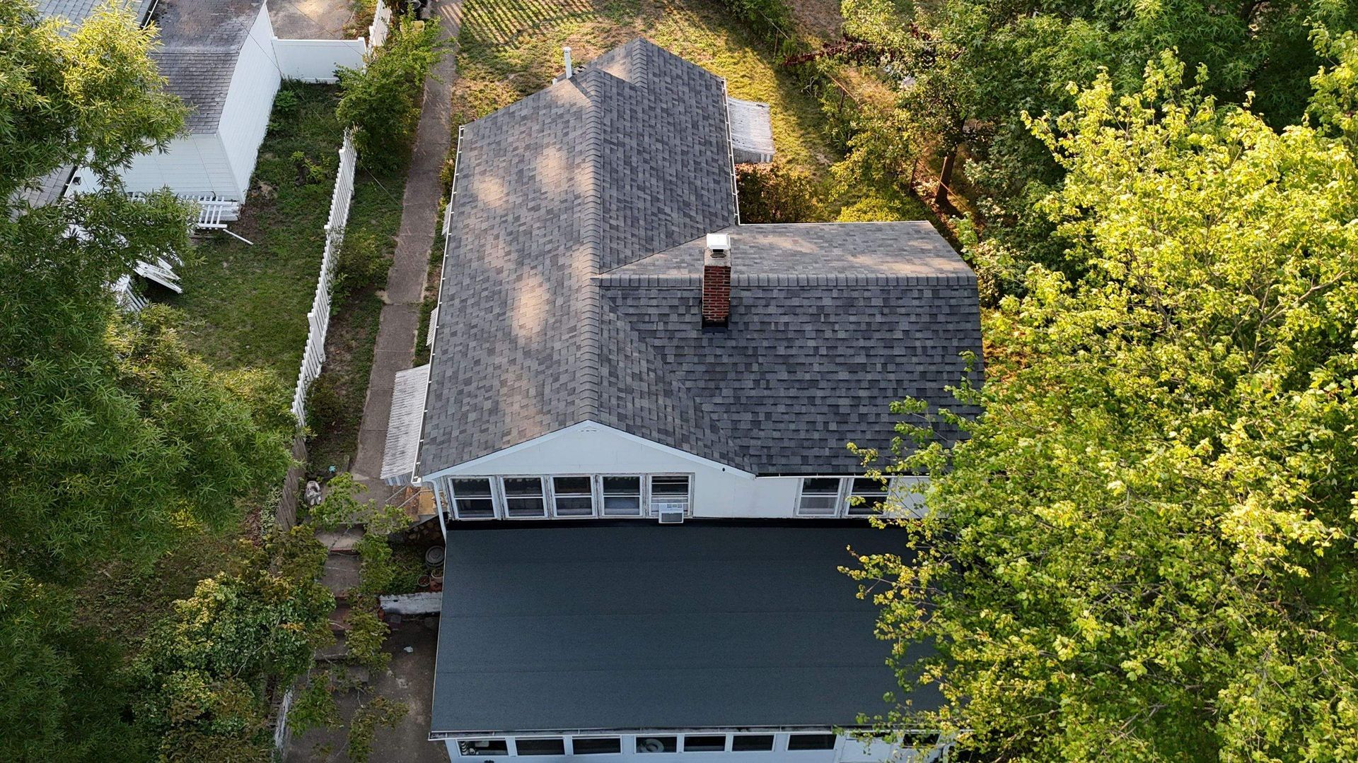 An aerial view of a house with a black roof surrounded by trees.