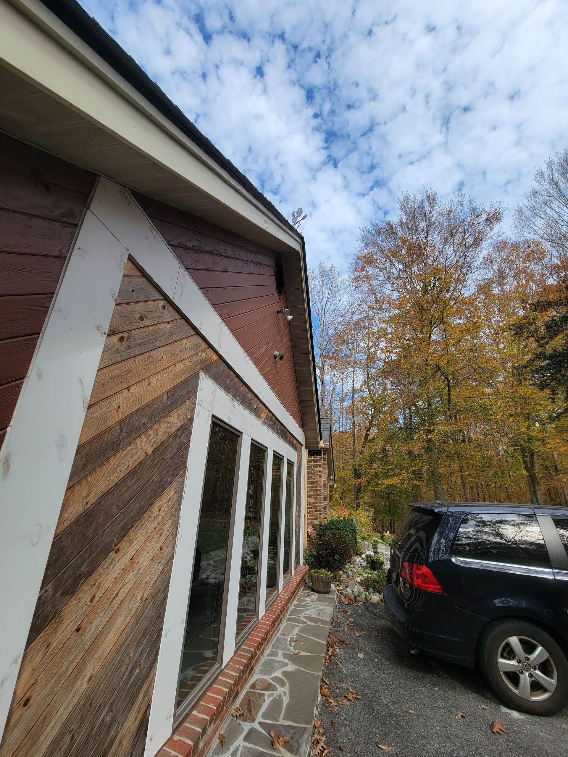 A car is parked in front of a house on a sunny day.