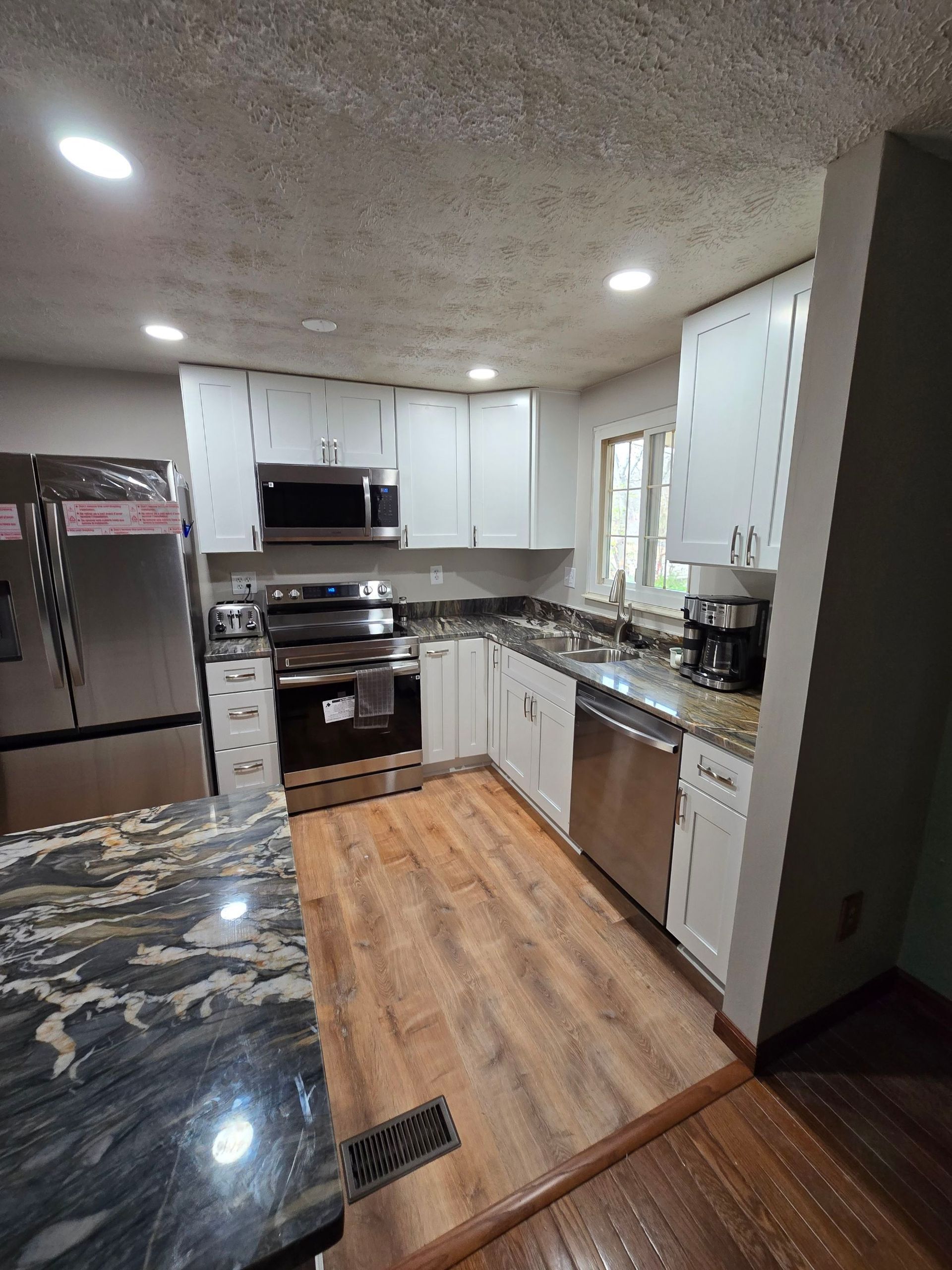 A kitchen with stainless steel appliances , granite counter tops , and white cabinets.