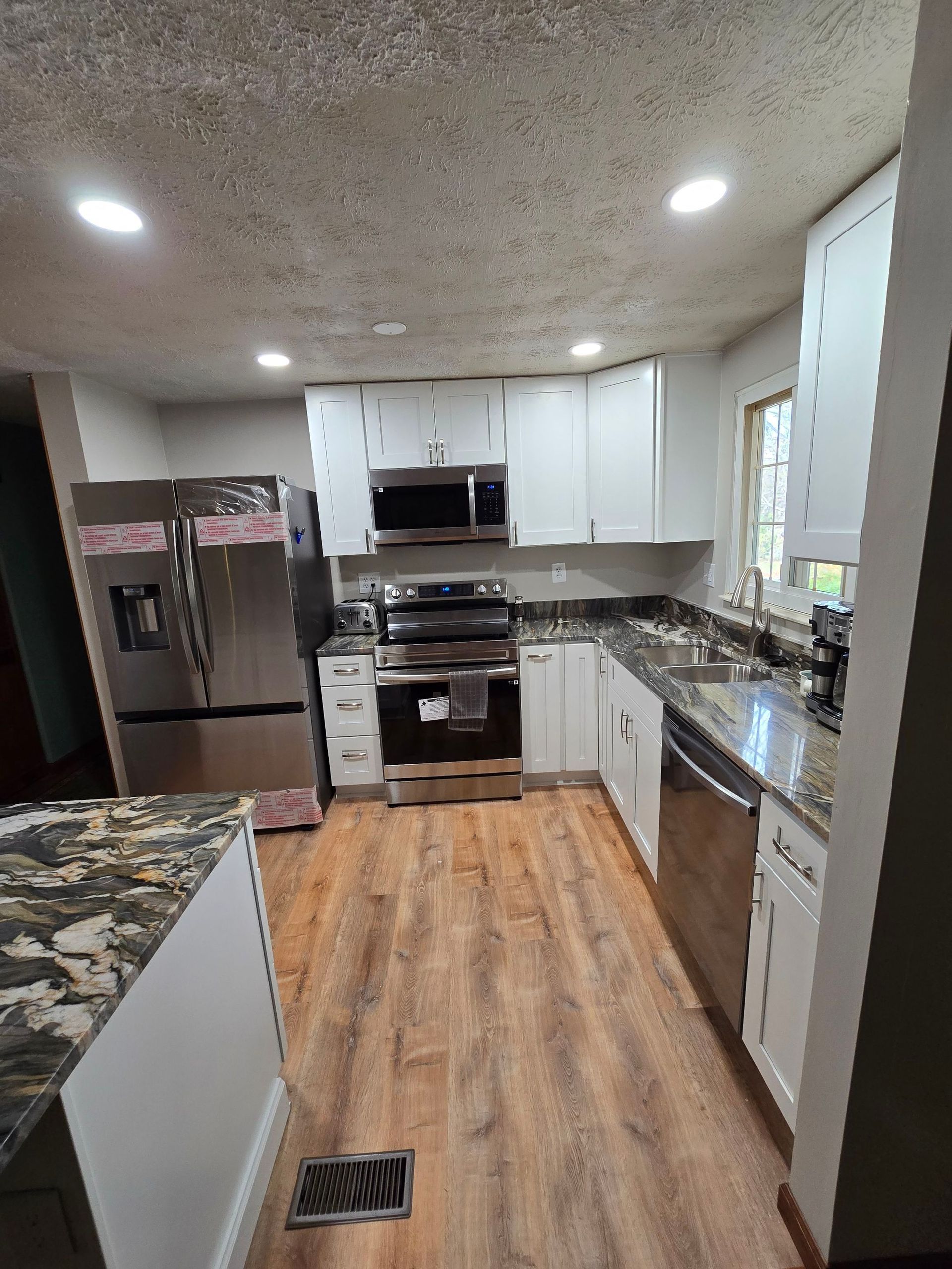 A kitchen with stainless steel appliances , granite counter tops , and white cabinets.