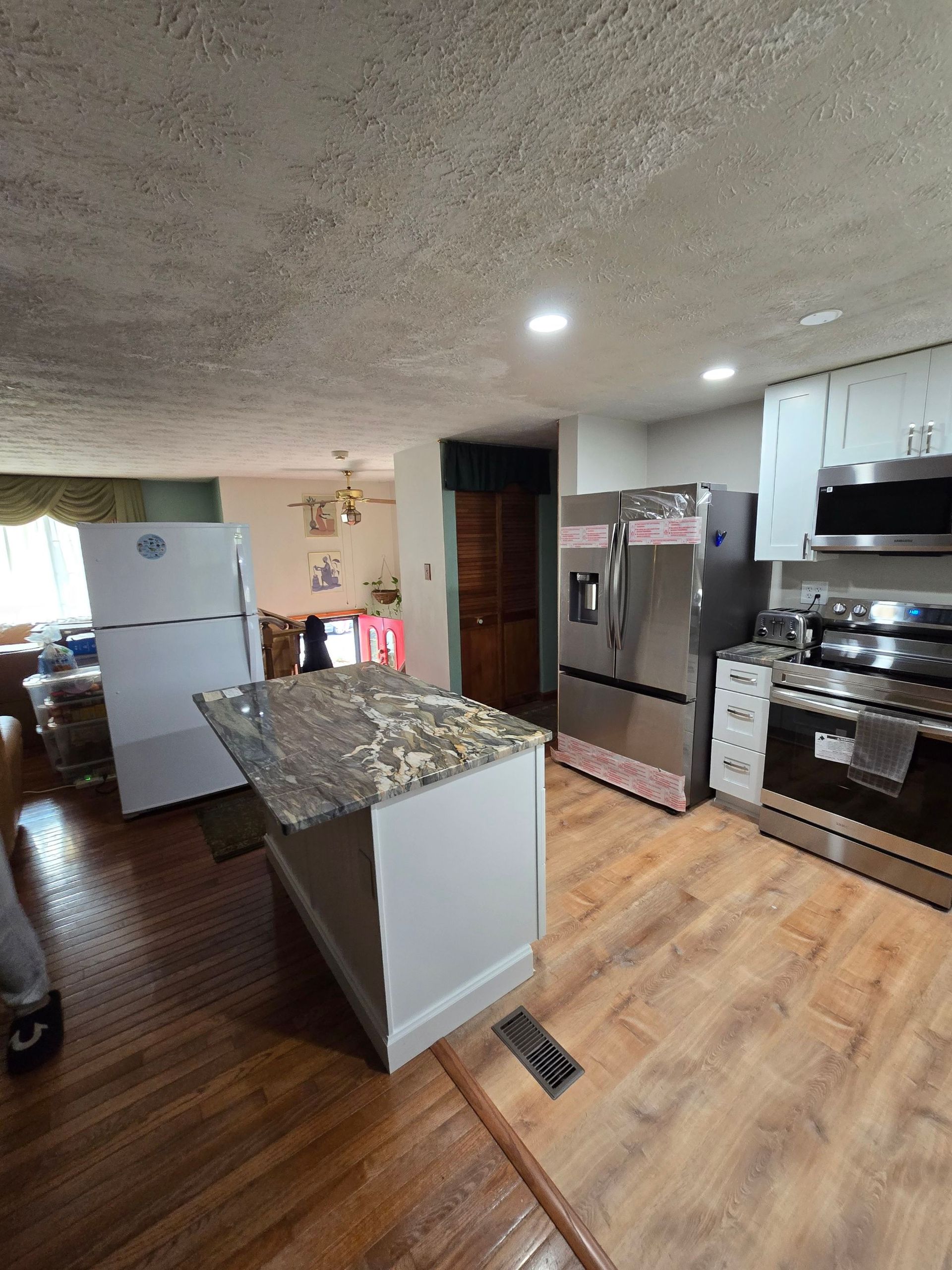 A kitchen with stainless steel appliances and a large island in the middle.