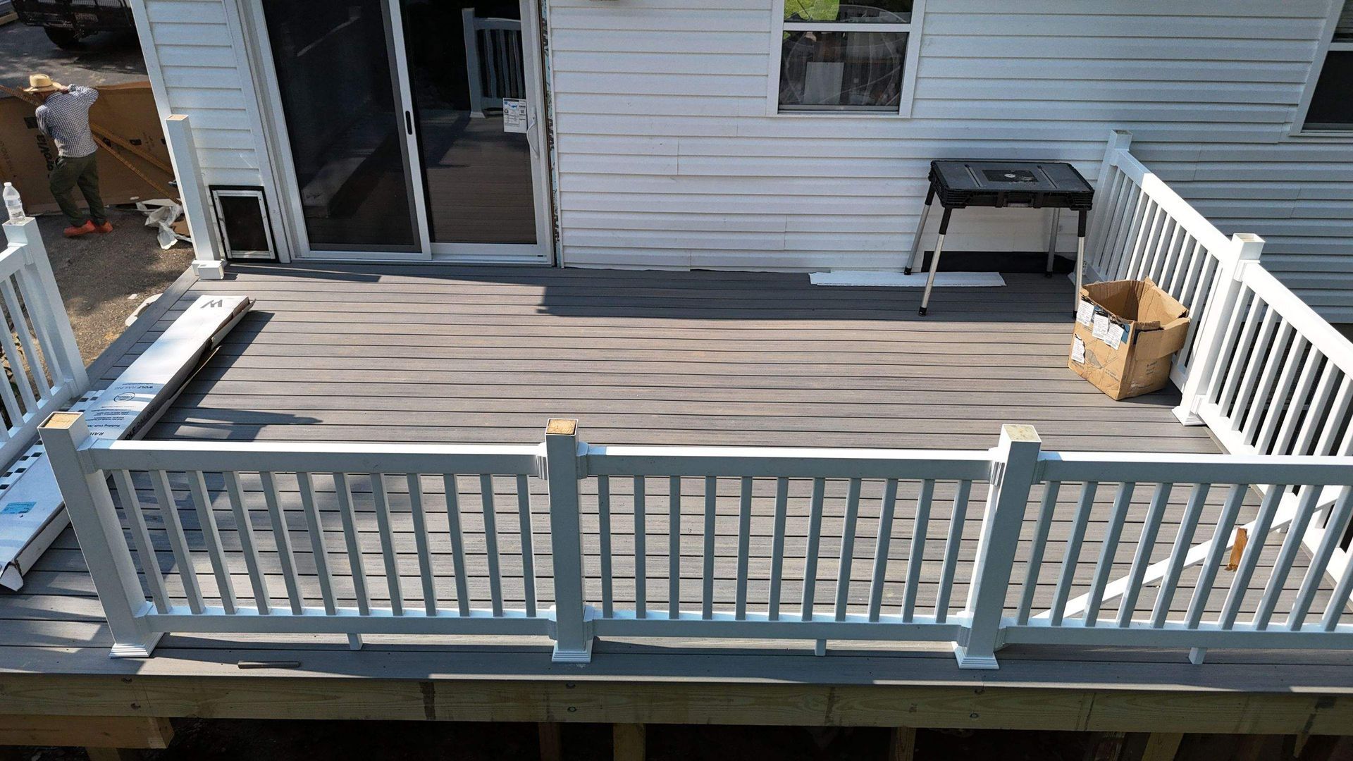 A deck with a white railing is being built in front of a white house.