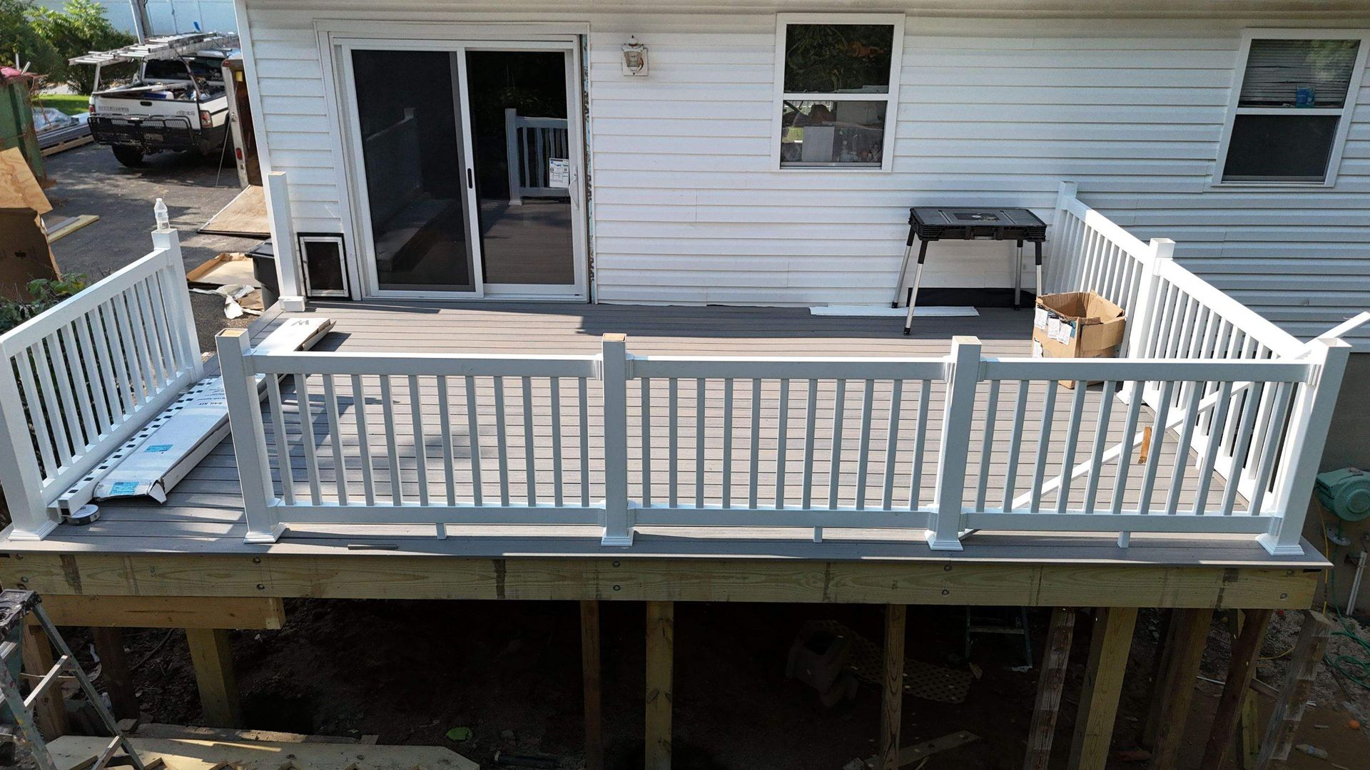 A white house with a large deck with a white railing