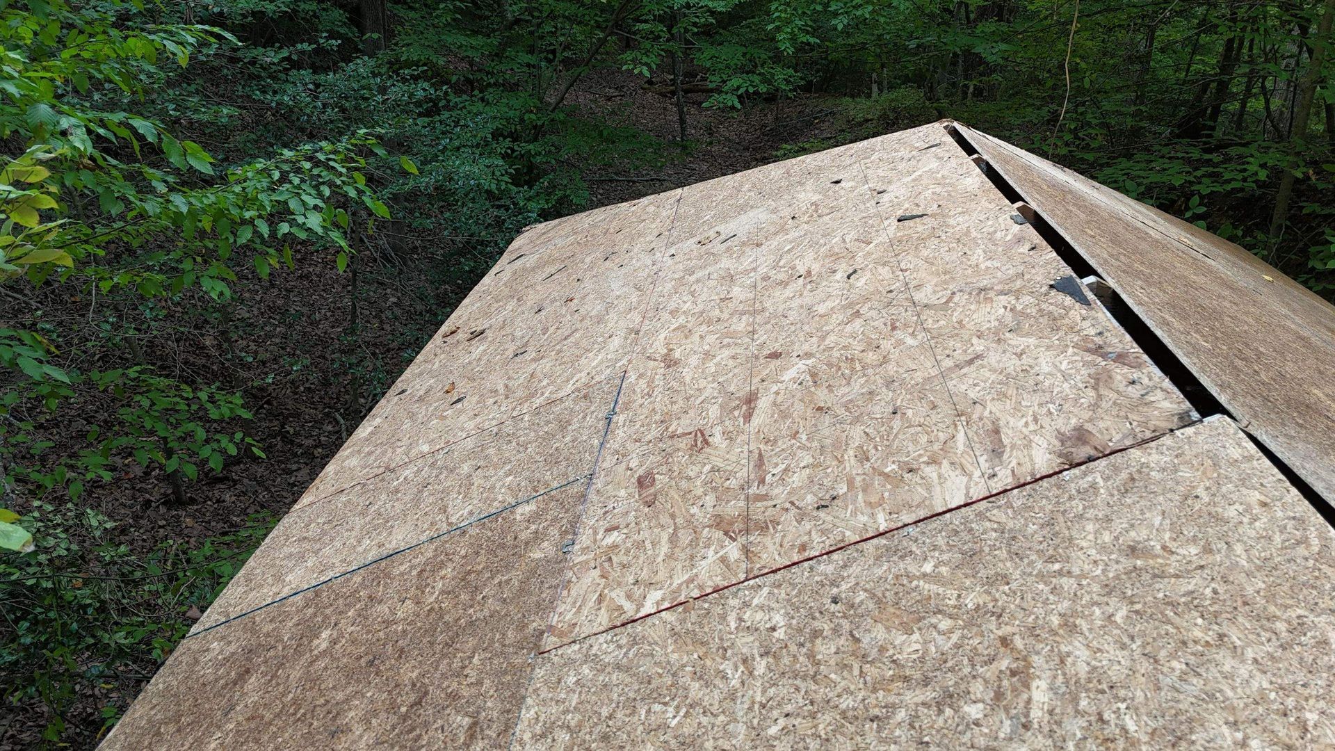 A close up of a wooden roof with trees in the background.