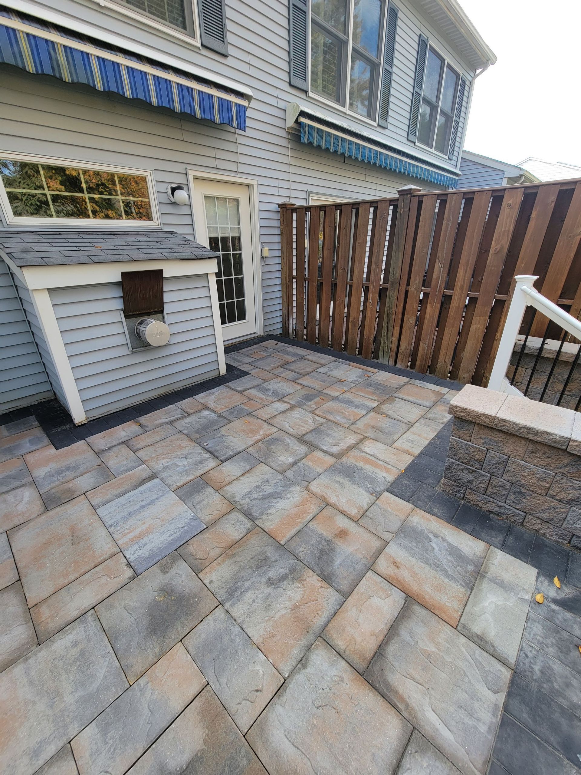 A patio with a wooden fence in front of a house.