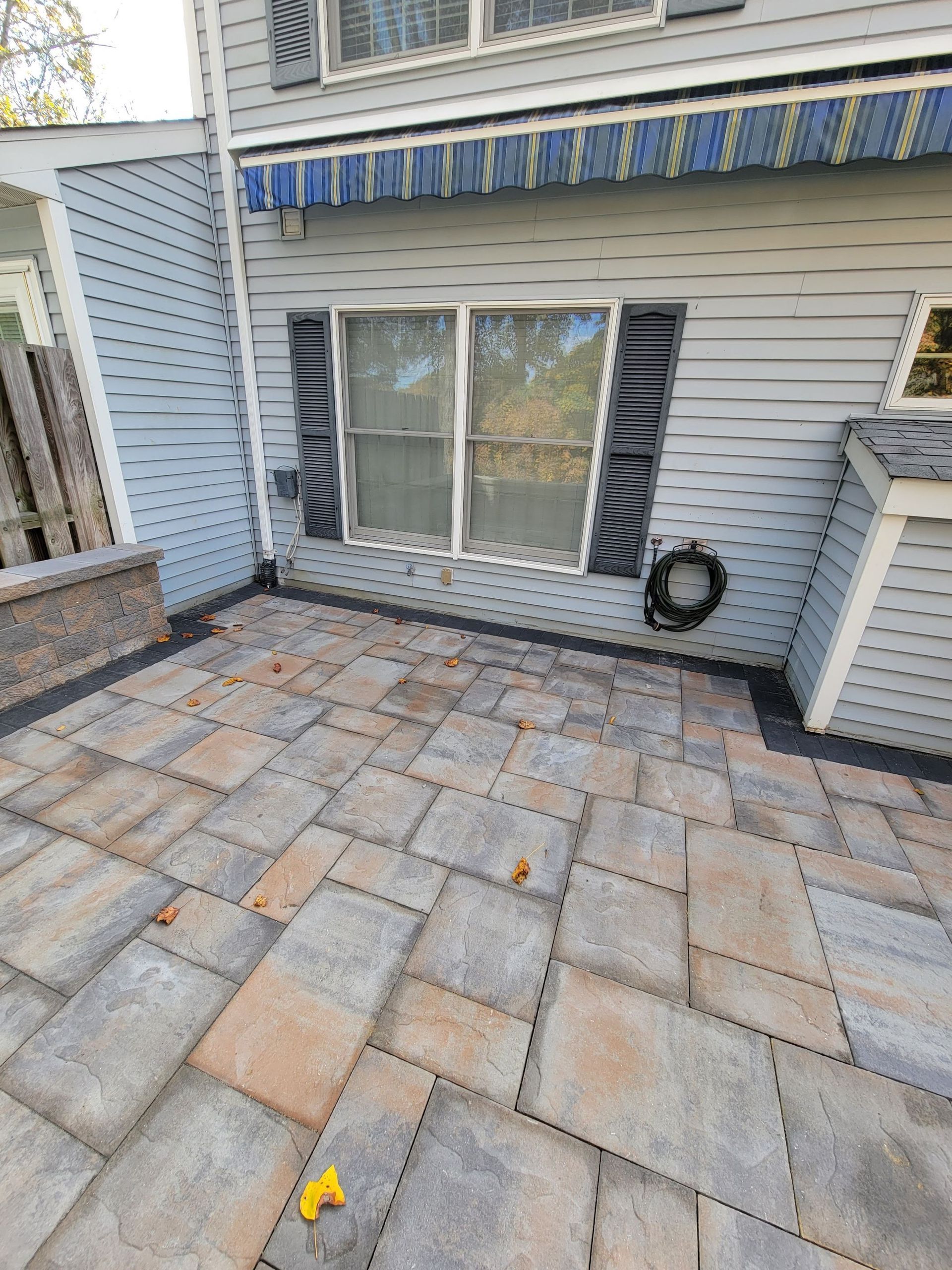 There is a patio in front of a house with a window.