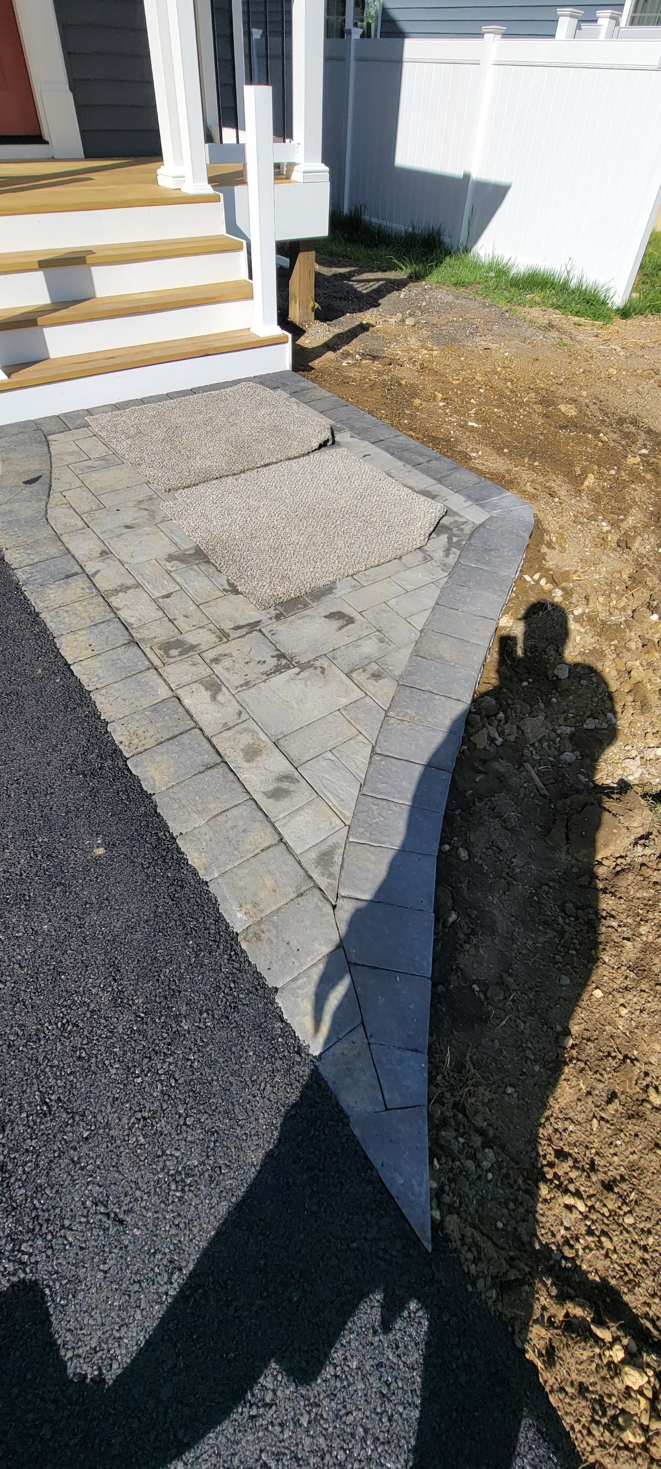 A shadow of a person is cast on the ground in front of a house.