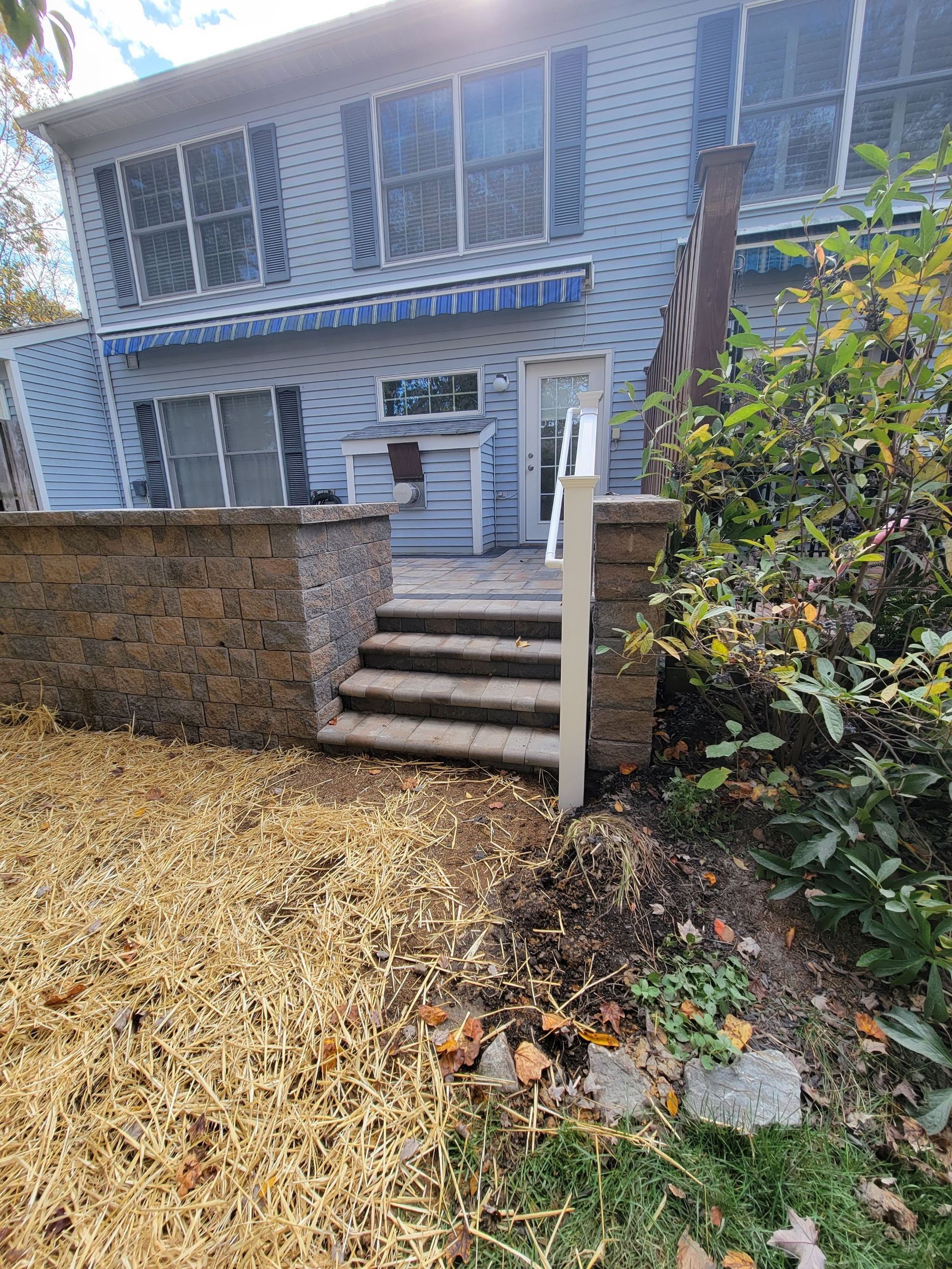 A house with stairs leading up to the backyard and a brick wall.