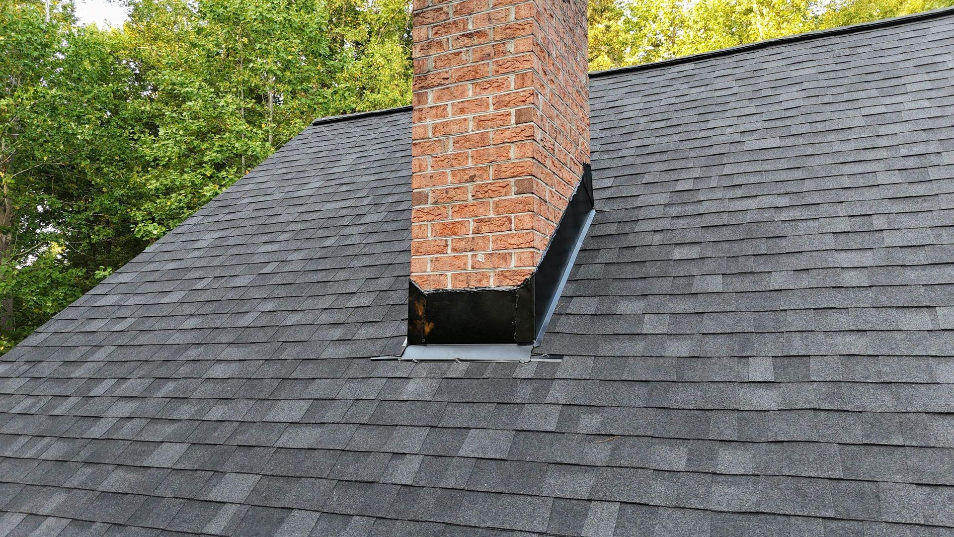 A brick chimney is sitting on top of a roof.