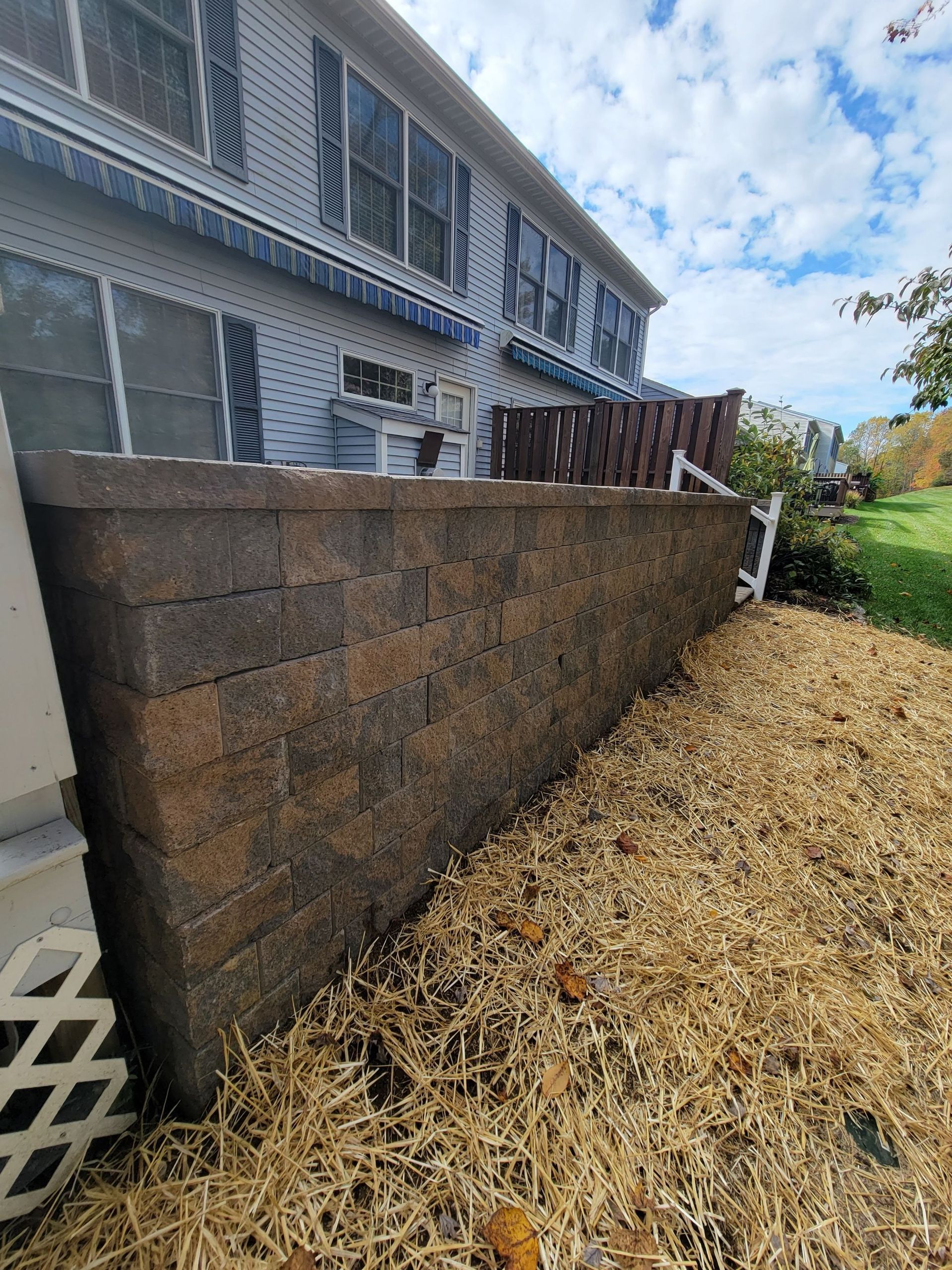 A large brick wall is sitting in front of a house.
