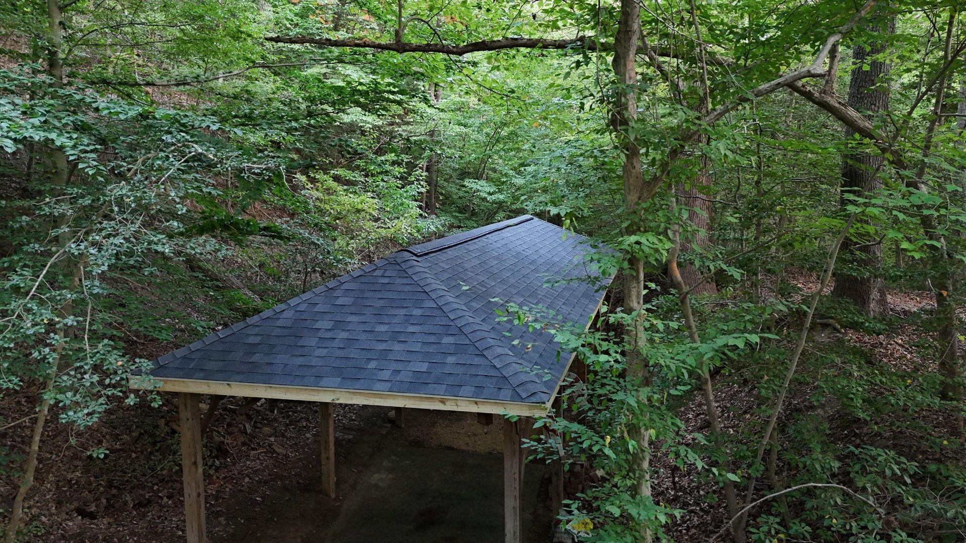 A gazebo in the middle of a forest surrounded by trees.