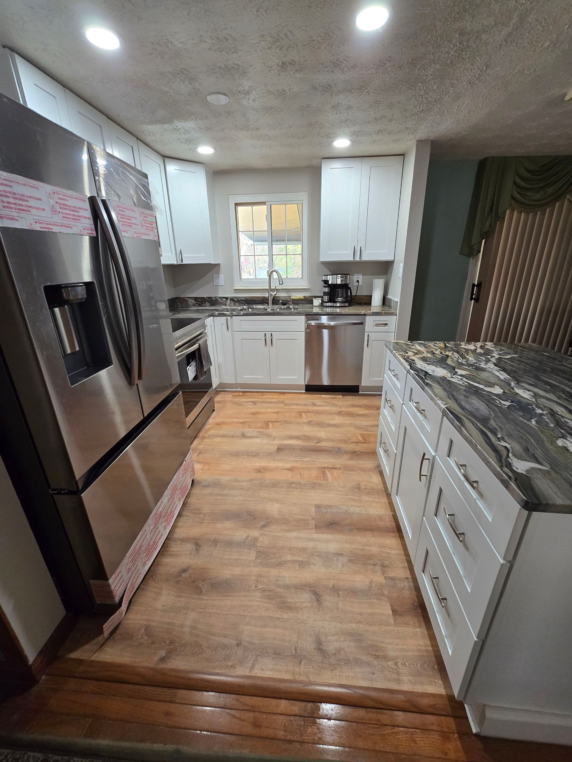 A kitchen with stainless steel appliances and wooden floors.